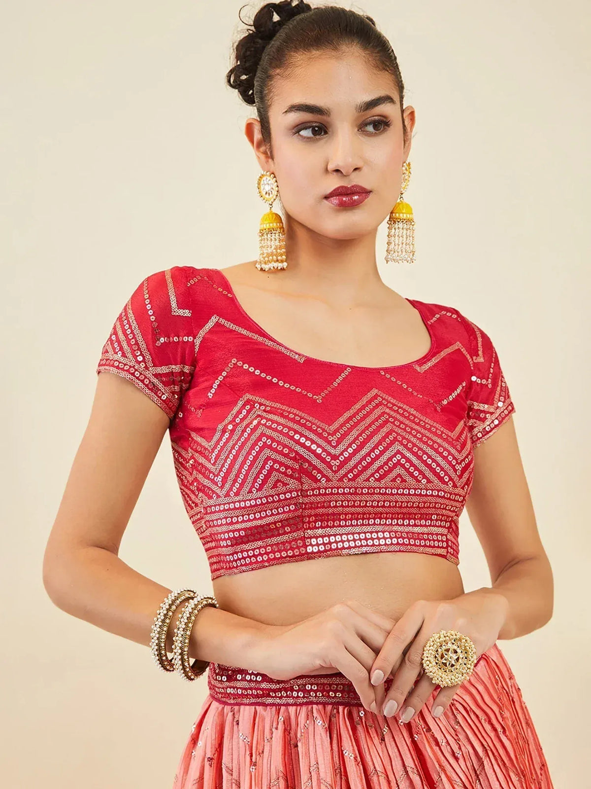 Red embroidered lehenga choli with gold jewelry and statement earrings