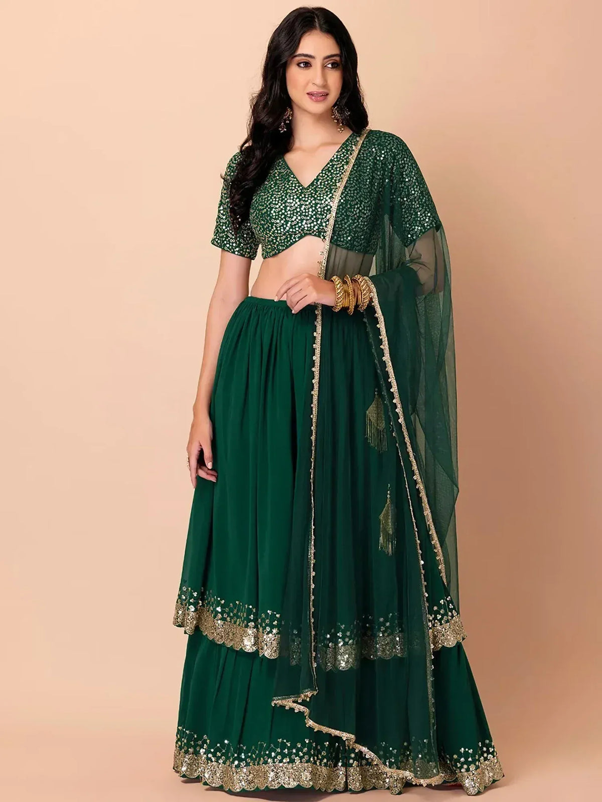 Emerald green sequin lehenga choli with gold embroidery and sheer dupatta, perfect for Indian ethnic occasions.