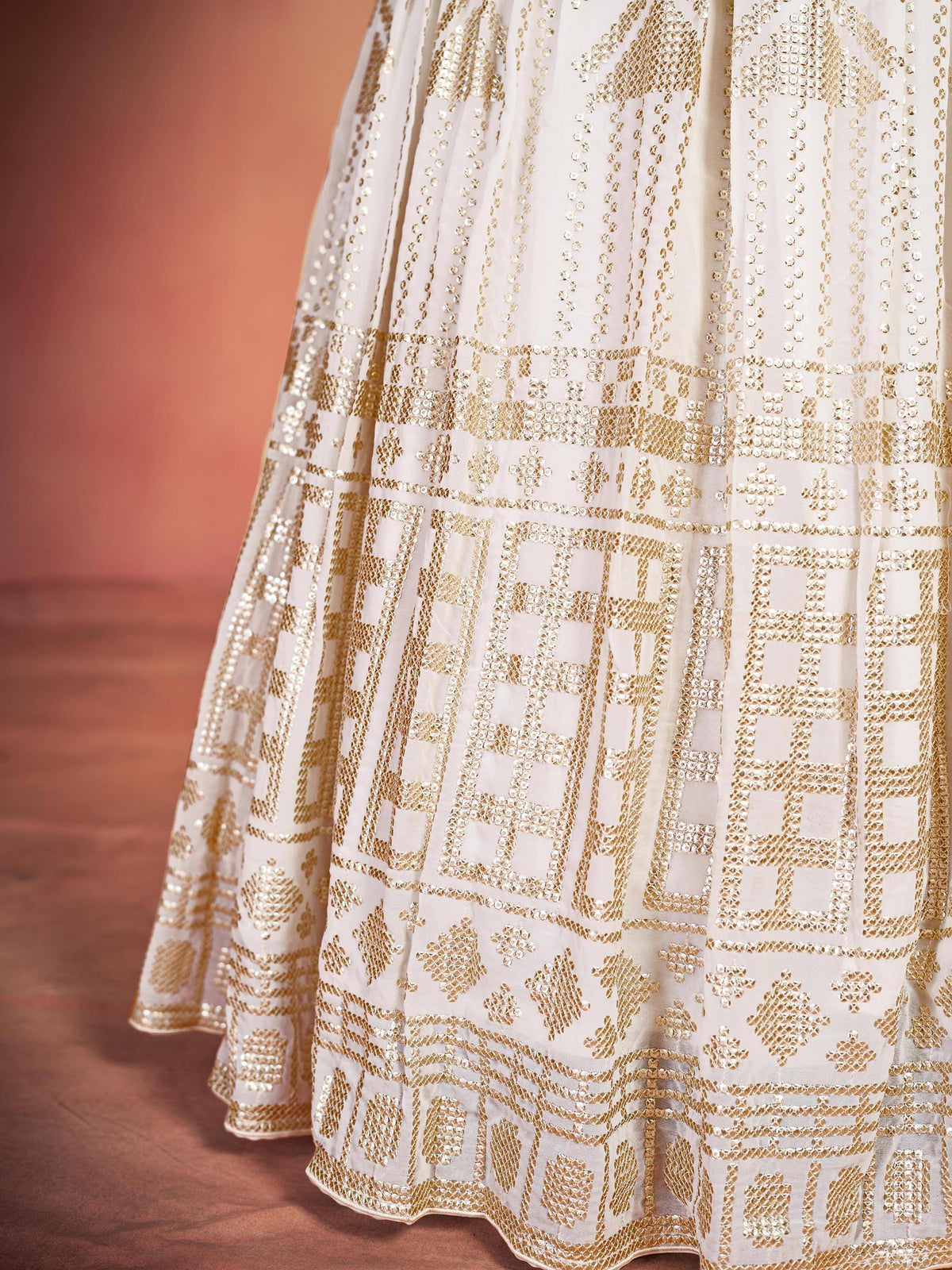 Cream lehenga with intricate gold geometric embroidery and sequin detailing for festive Indian wear