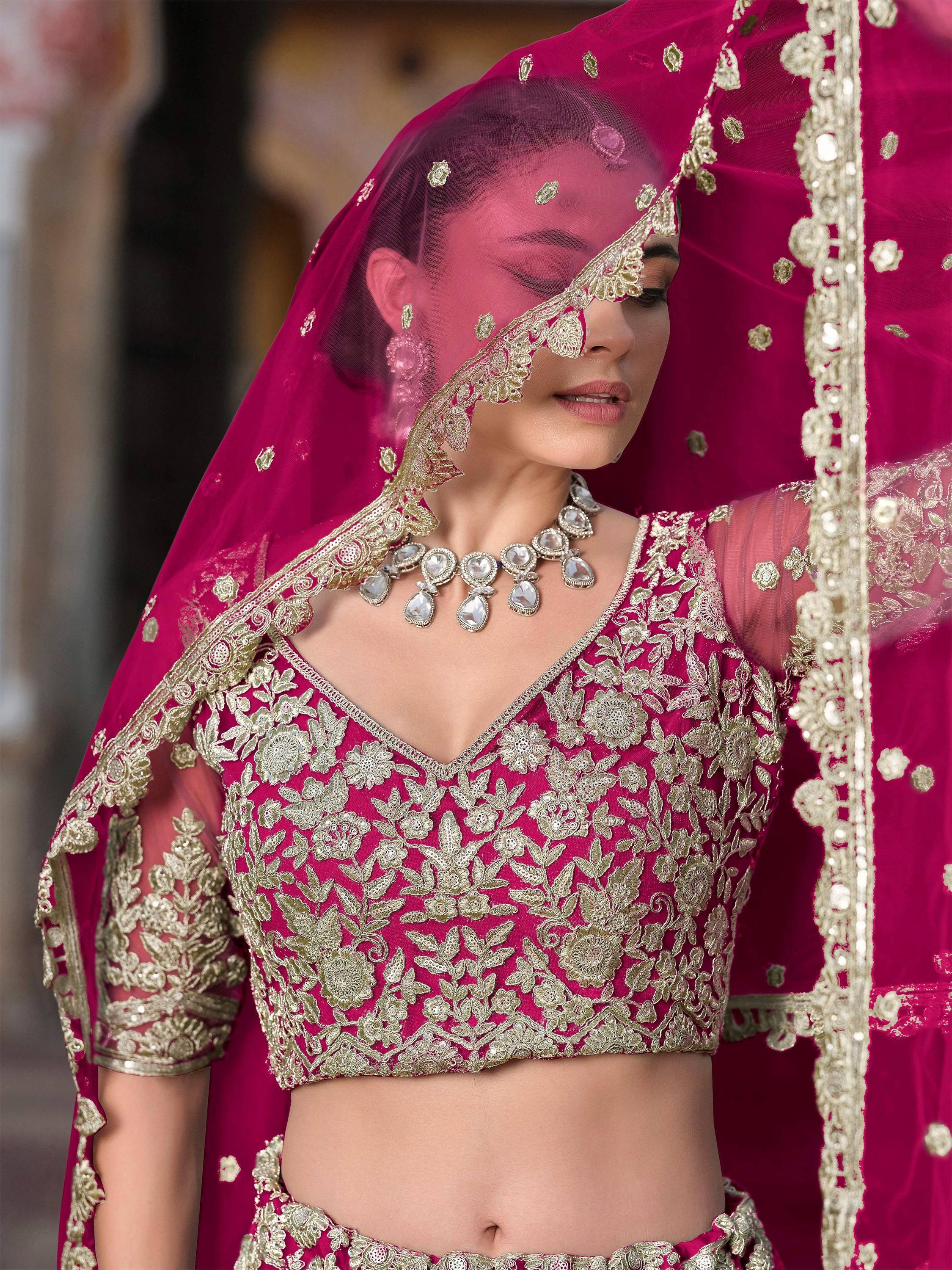 Fuchsia lehenga choli with gold floral embroidery and sheer dupatta, perfect for Indian weddings and festive occasions.