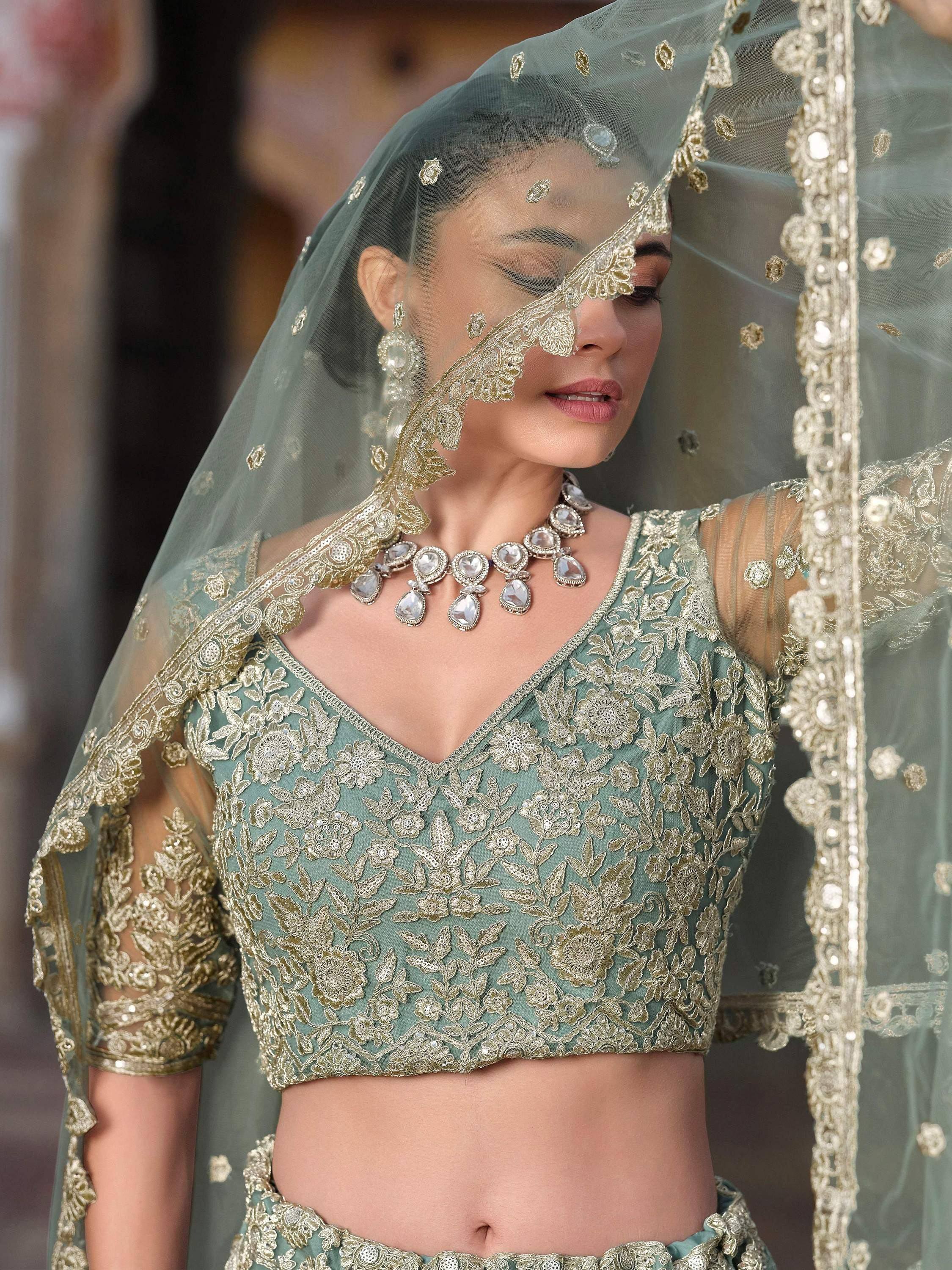 Elegant sage green lehenga choli with gold floral embroidery and sheer dupatta for Indian weddings