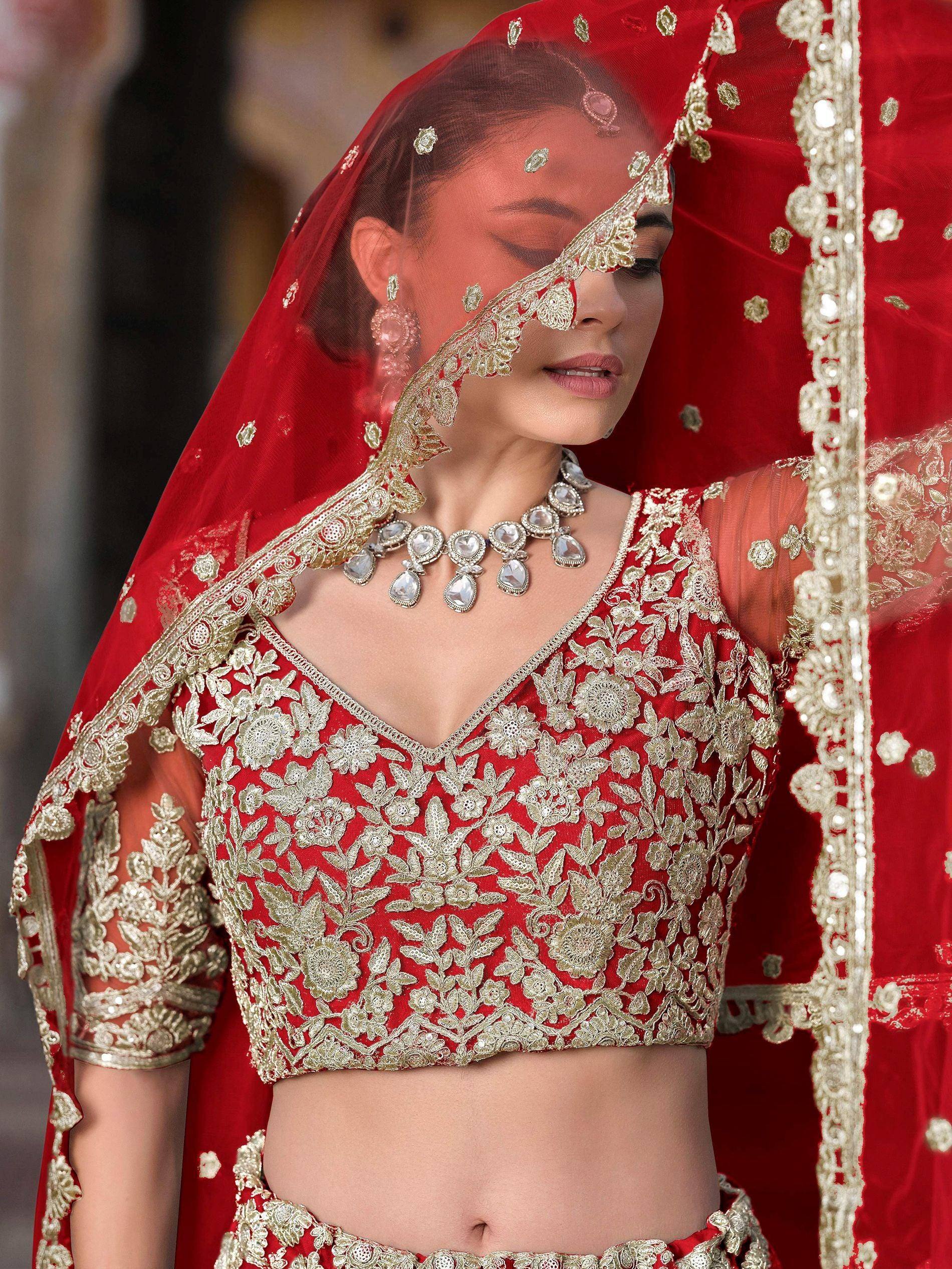 Red and gold embroidered lehenga choli with sheer dupatta, perfect for Indian weddings and ethnic events.