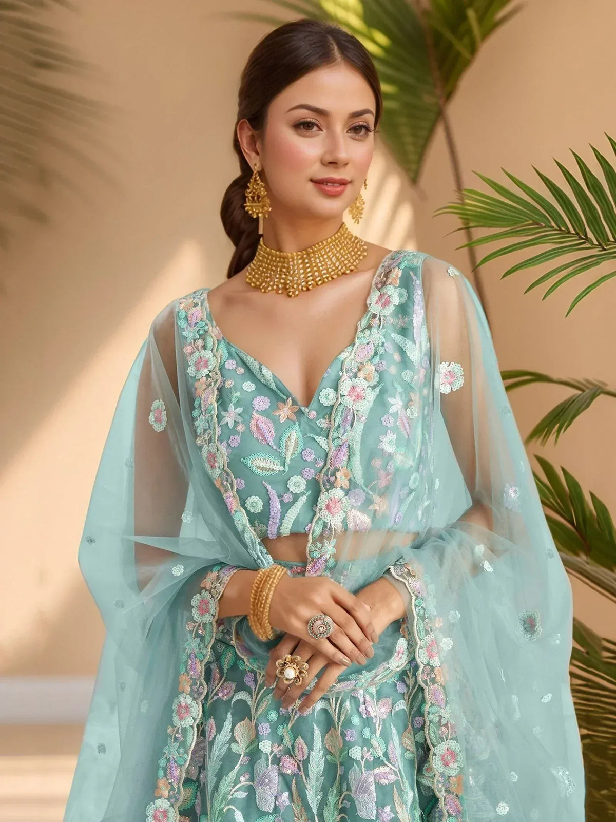 Mint green embroidered lehenga choli with floral detailing, sheer dupatta, and gold jewelry for Indian ethnic wear