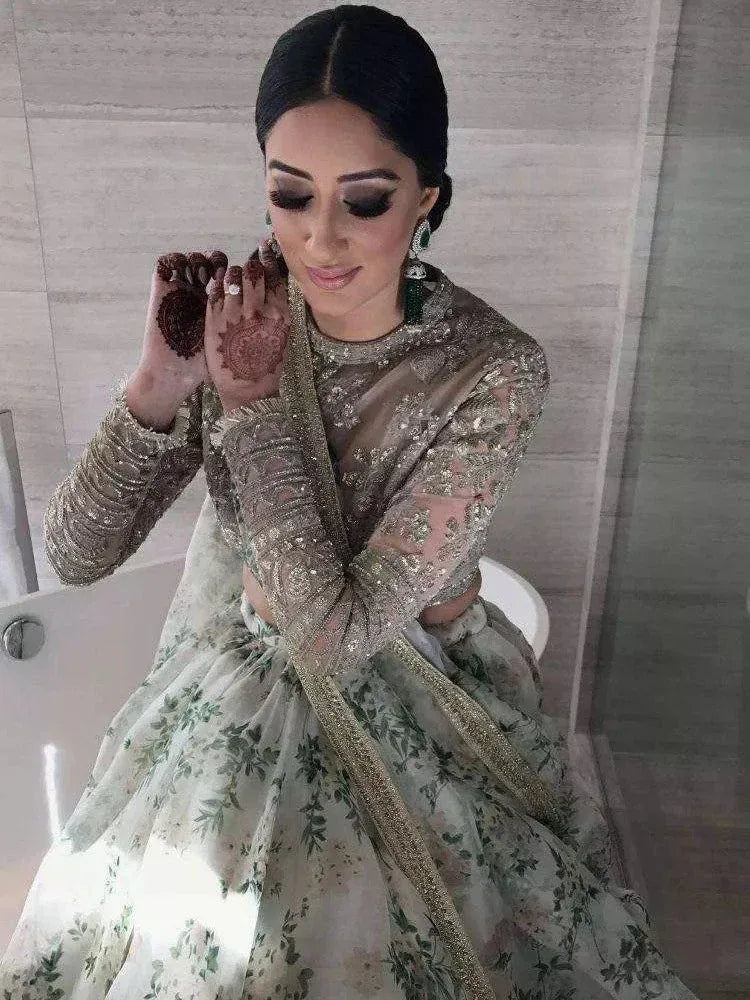 Elegant Indian bride in floral lehenga choli with intricate henna and green earrings