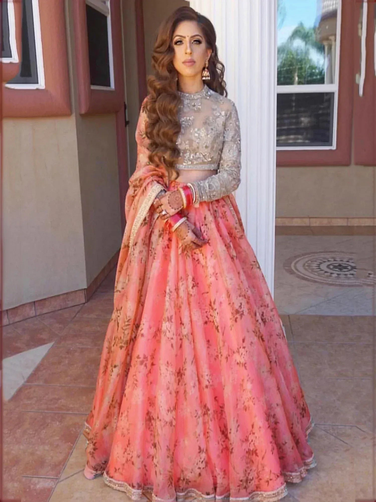 Woman in pink floral lehenga choli with silver embellished blouse, perfect for Indian weddings and festive occasions.