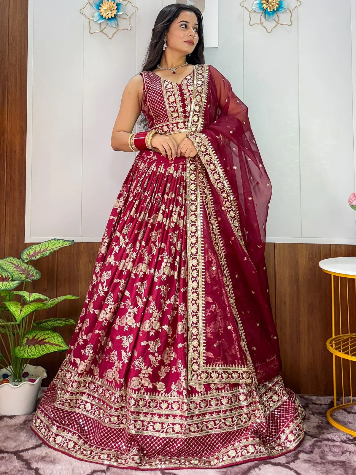 Maroon designer lehenga choli with gold floral embroidery and sheer dupatta, perfect for Indian weddings and festivals.