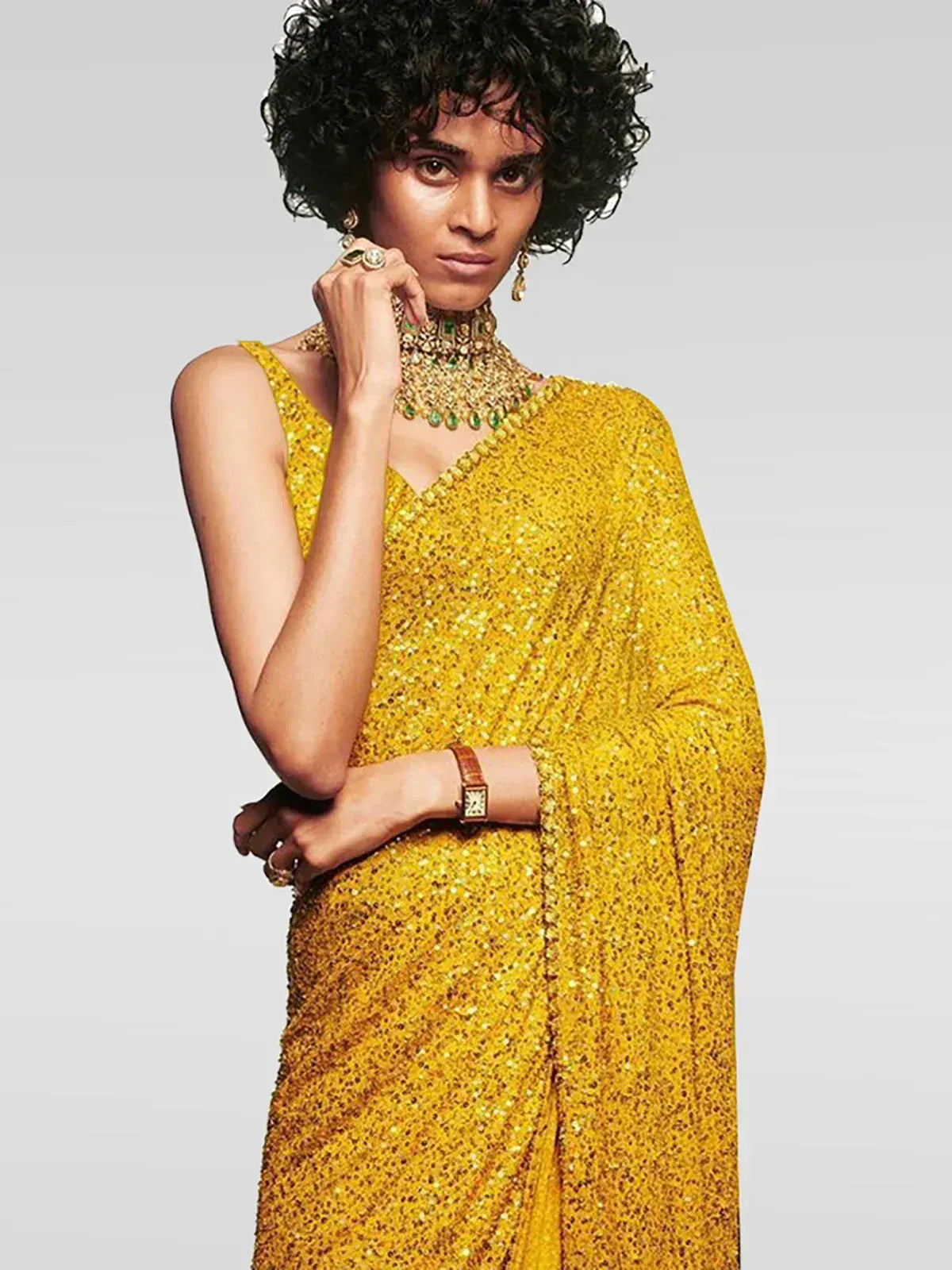 Woman in shimmering yellow sequin saree with emerald jewelry, Indian ethnic wear