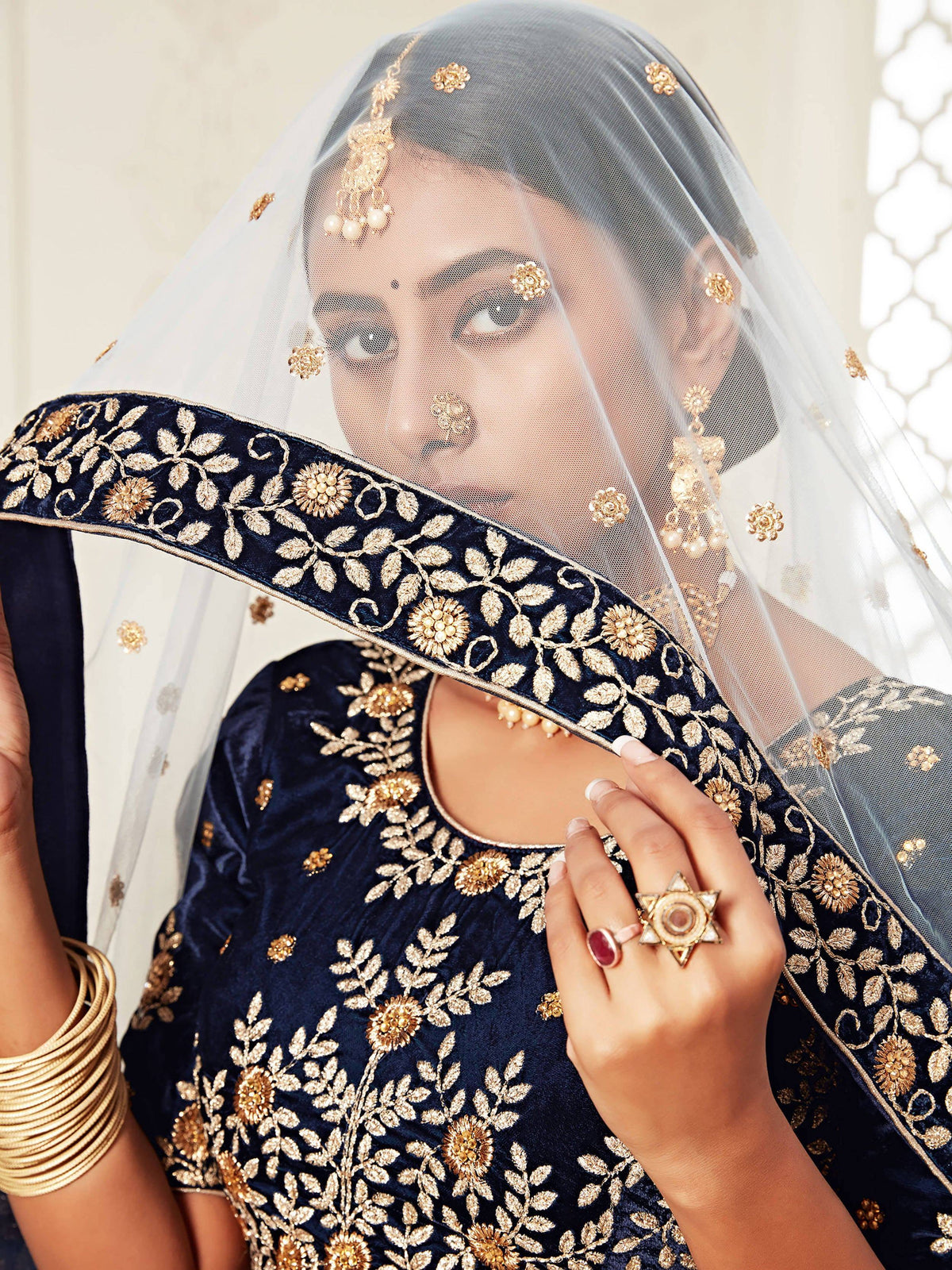 Woman in navy blue velvet ethnic wear with gold embroidery and sheer bridal veil