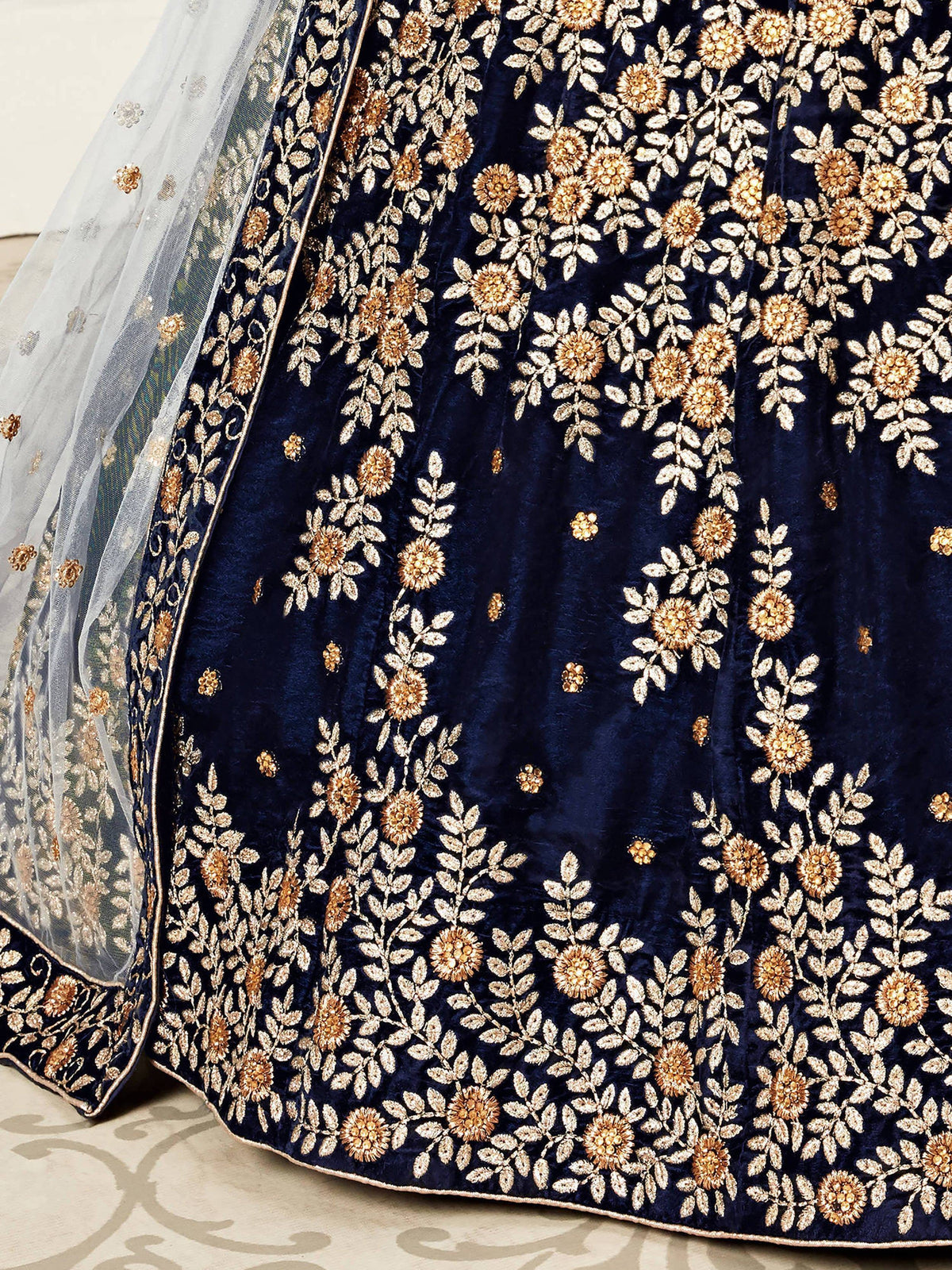 Close-up of a navy blue velvet lehenga with gold floral embroidery and a sheer dupatta