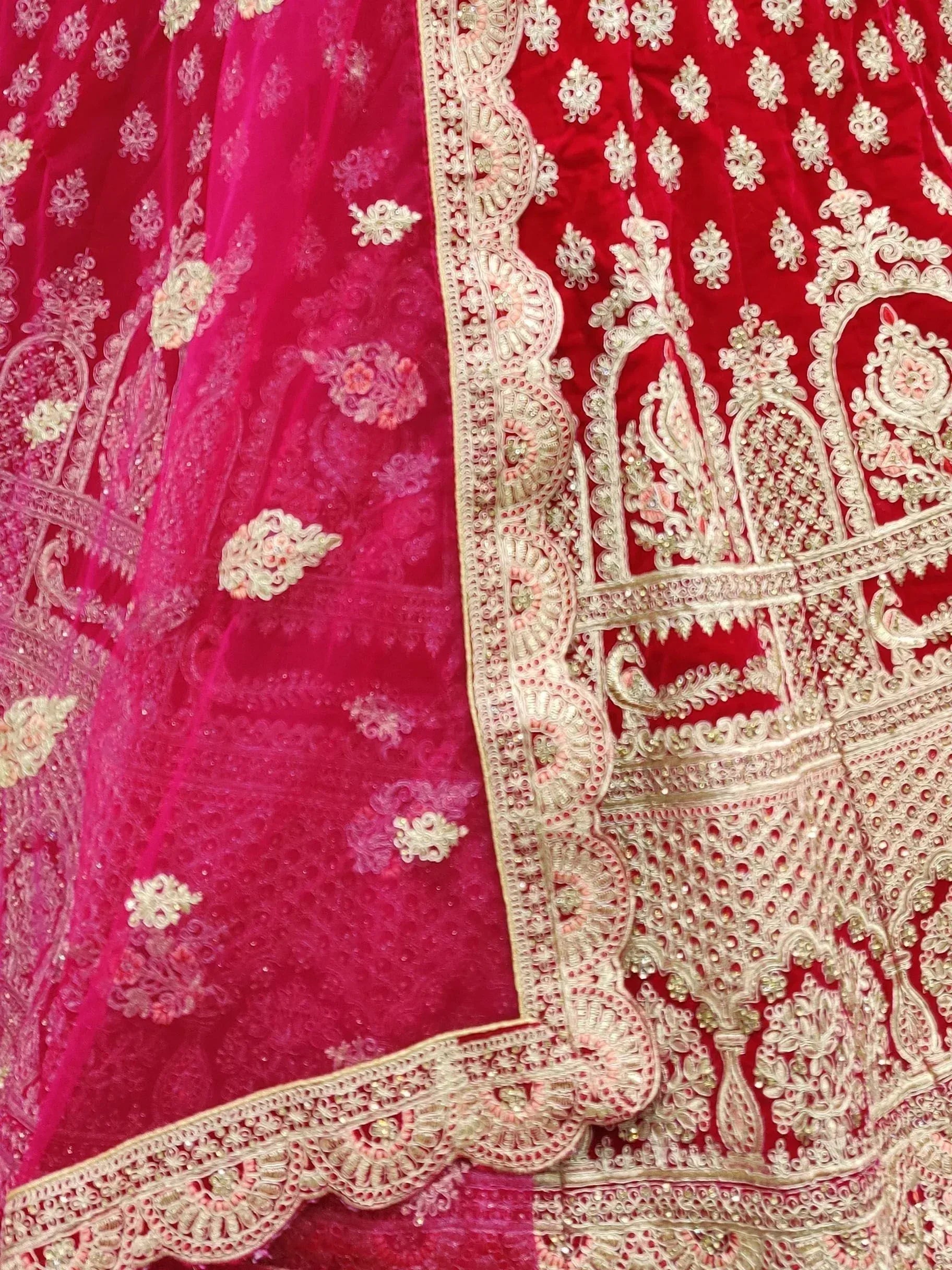 Red and pink velvet lehenga choli with intricate gold embroidery and floral motifs, perfect for Indian weddings.