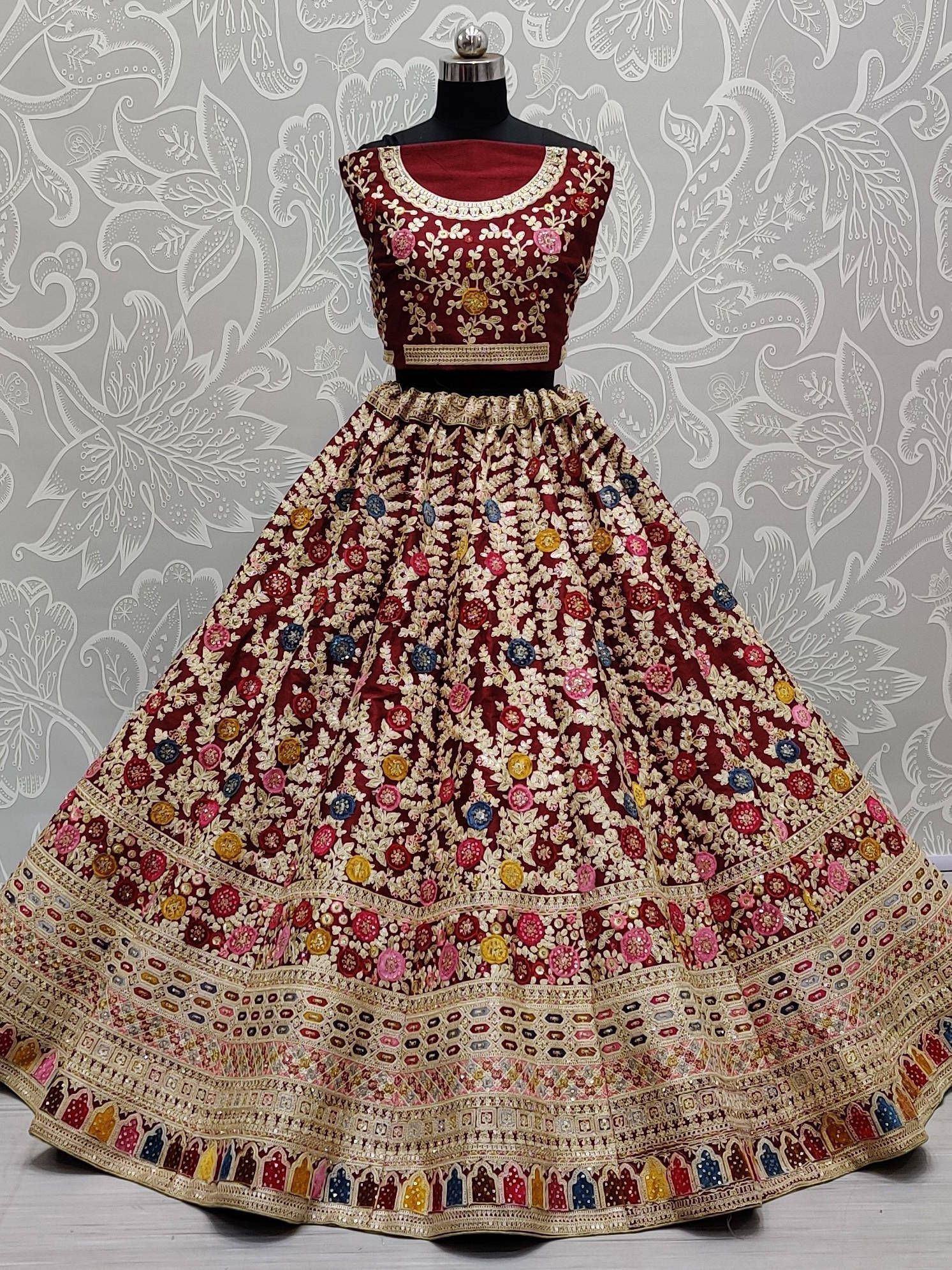 Maroon embroidered lehenga choli with floral motifs and colorful mirror work, perfect for Indian weddings and festive occasions.