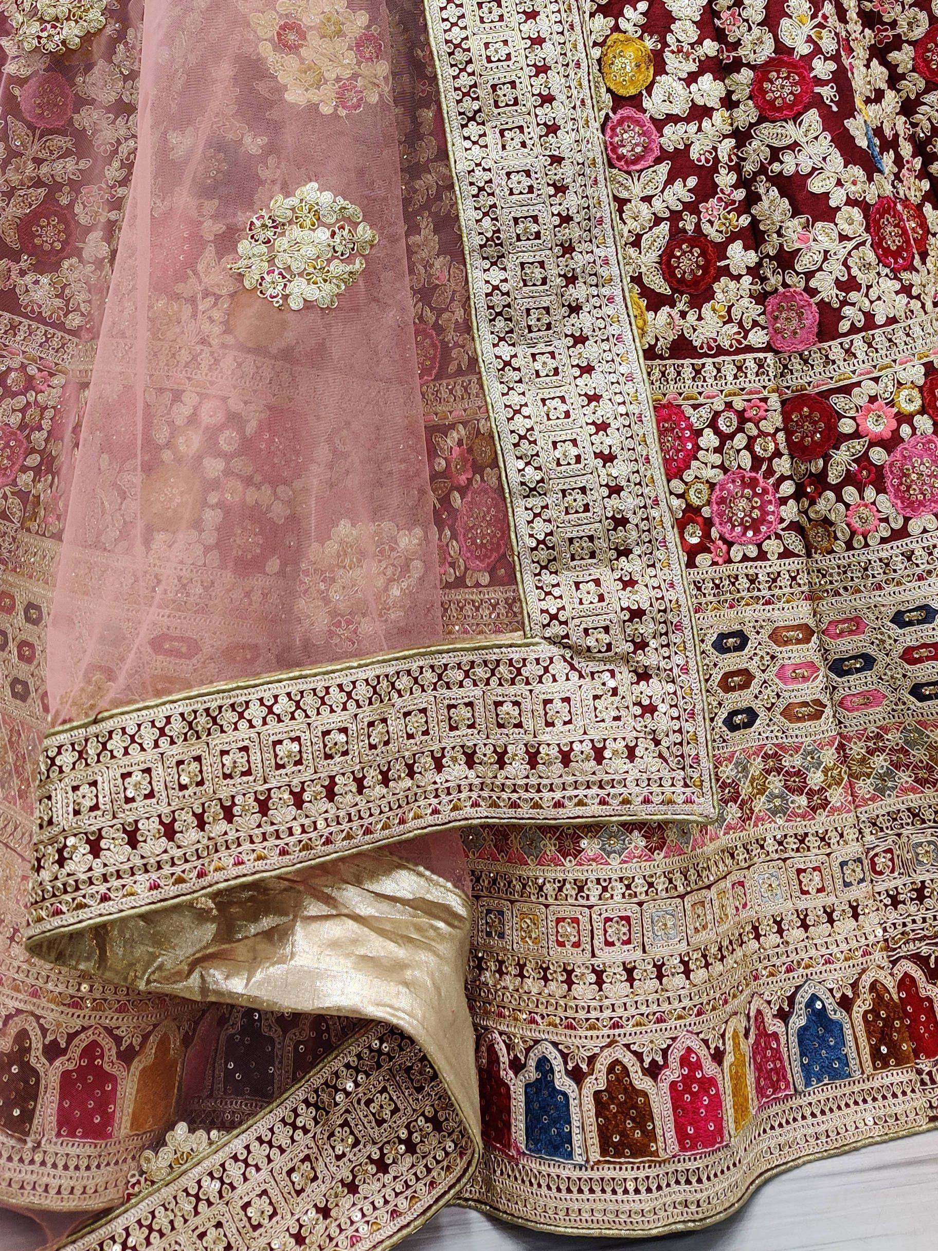 Luxury maroon lehenga choli with intricate gold embroidery, floral motifs, and sheer dupatta for Indian weddings