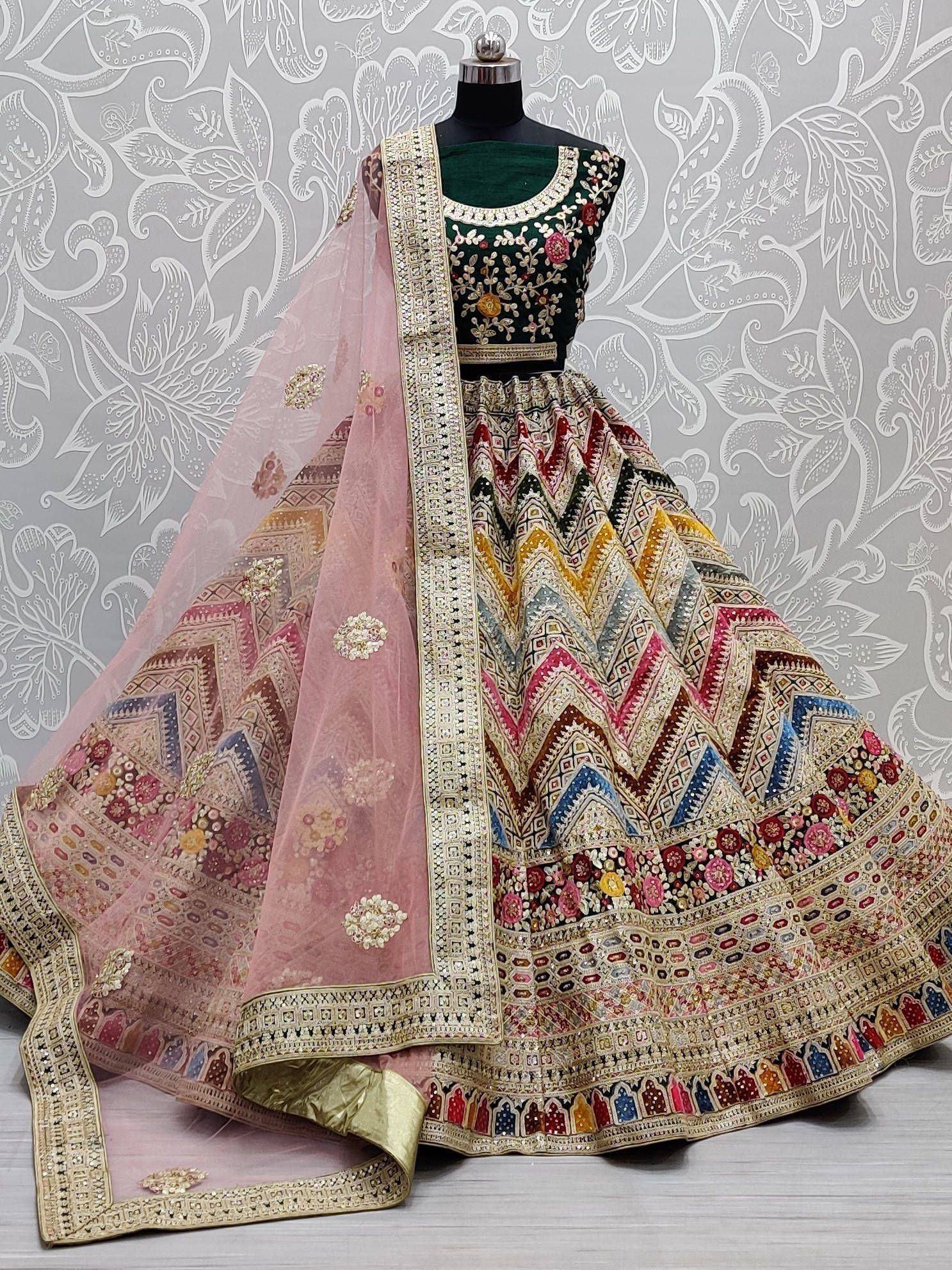 Designer lehenga choli with embroidered green blouse, colorful geometric skirt, and pink dupatta for Indian ethnic wear