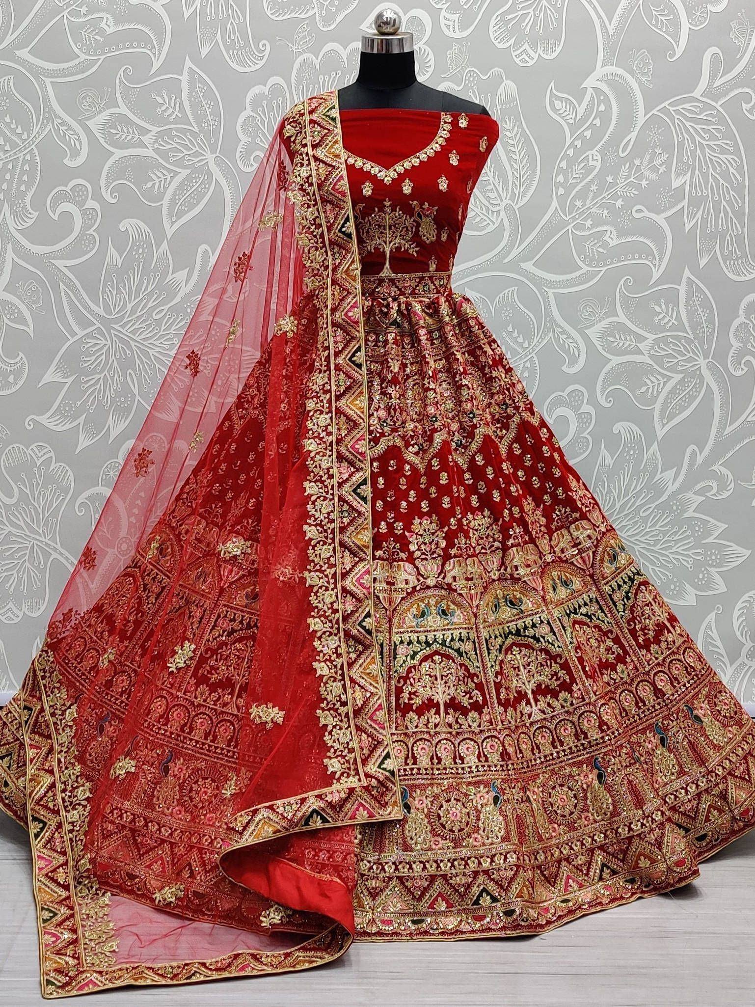 Red velvet designer lehenga choli with gold embroidery and sheer dupatta, perfect for weddings and festive occasions.