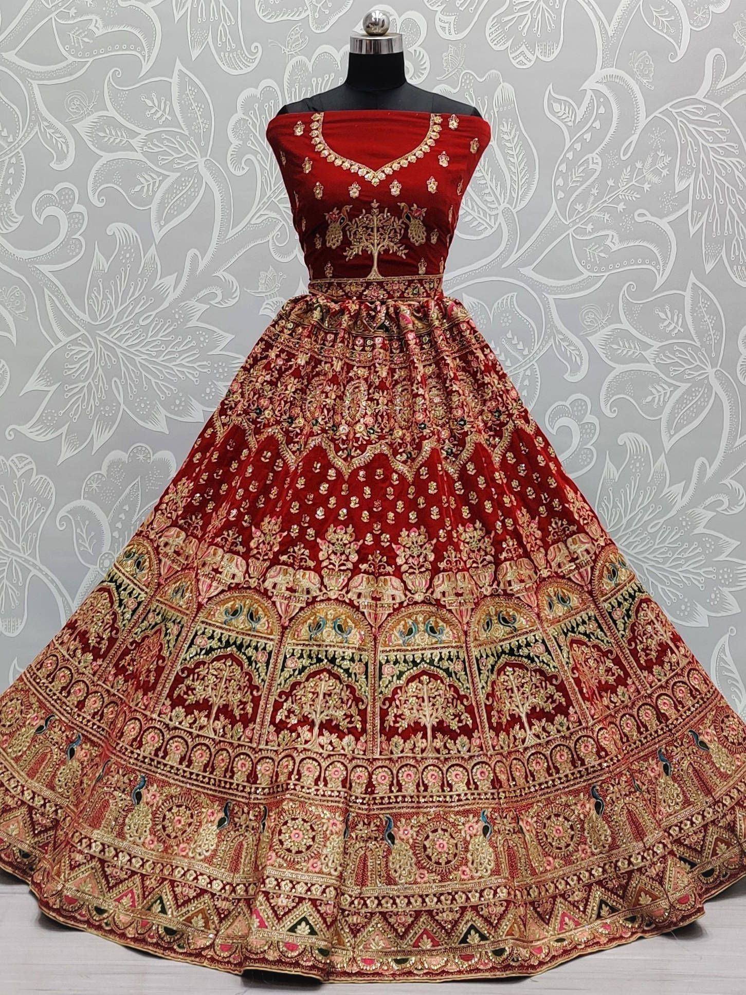 Red velvet designer lehenga with gold embroidery and peacock motifs, perfect for Indian weddings and festivals