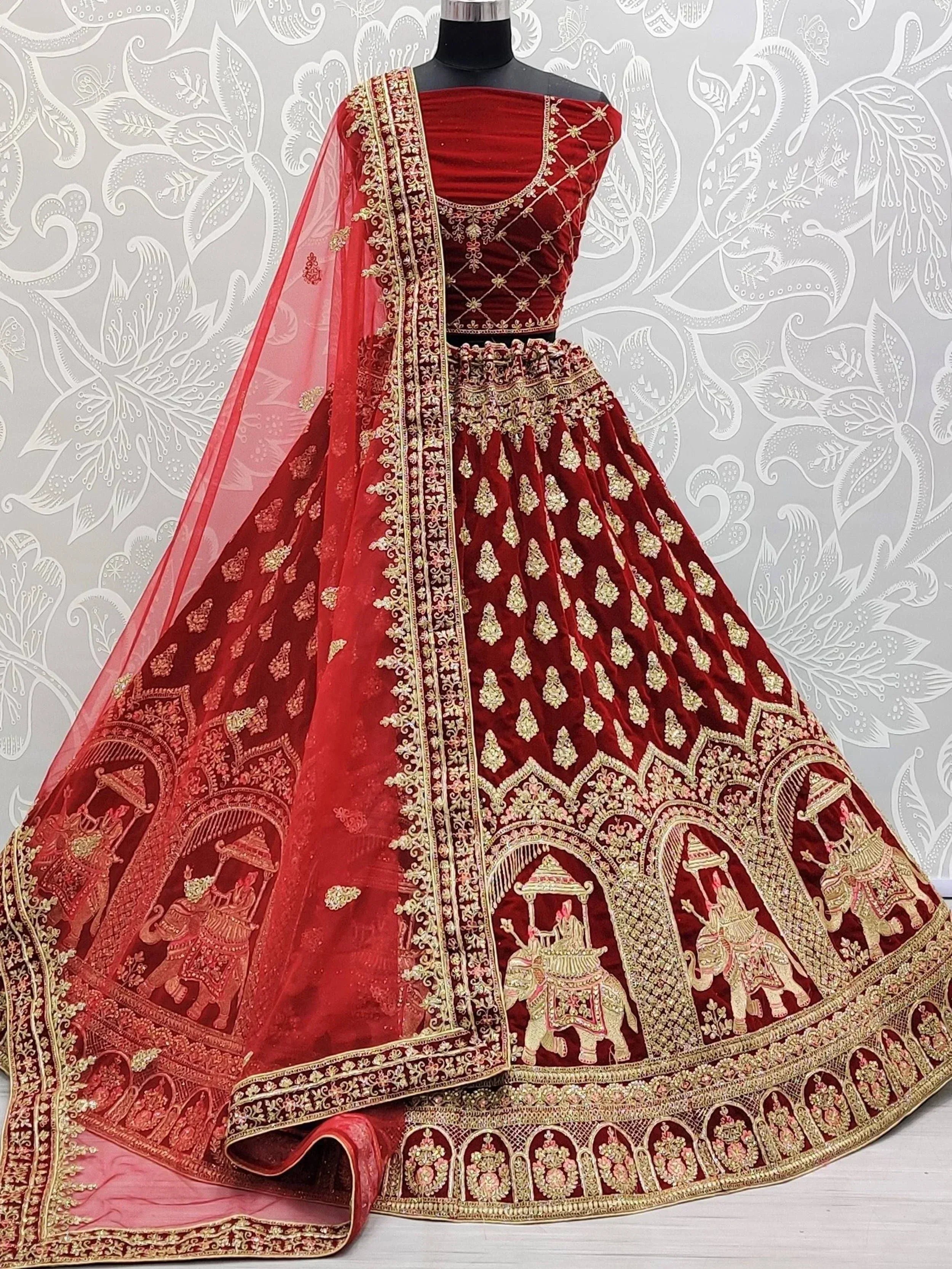 Red velvet designer lehenga choli with gold embroidery and elephant motifs, perfect for Indian weddings.
