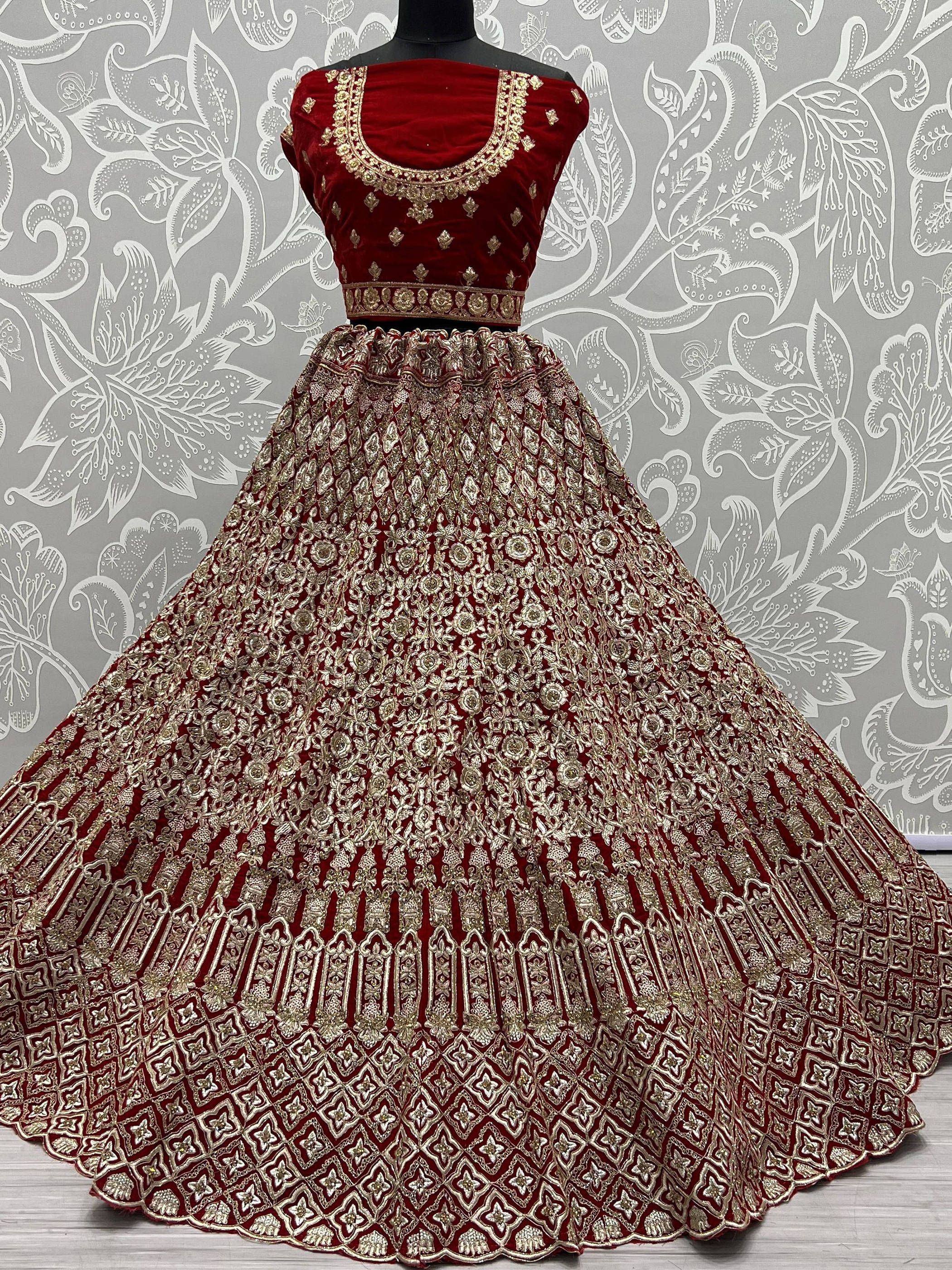 Red velvet designer lehenga choli with heavy gold embroidery, perfect for Indian weddings and festive occasions.