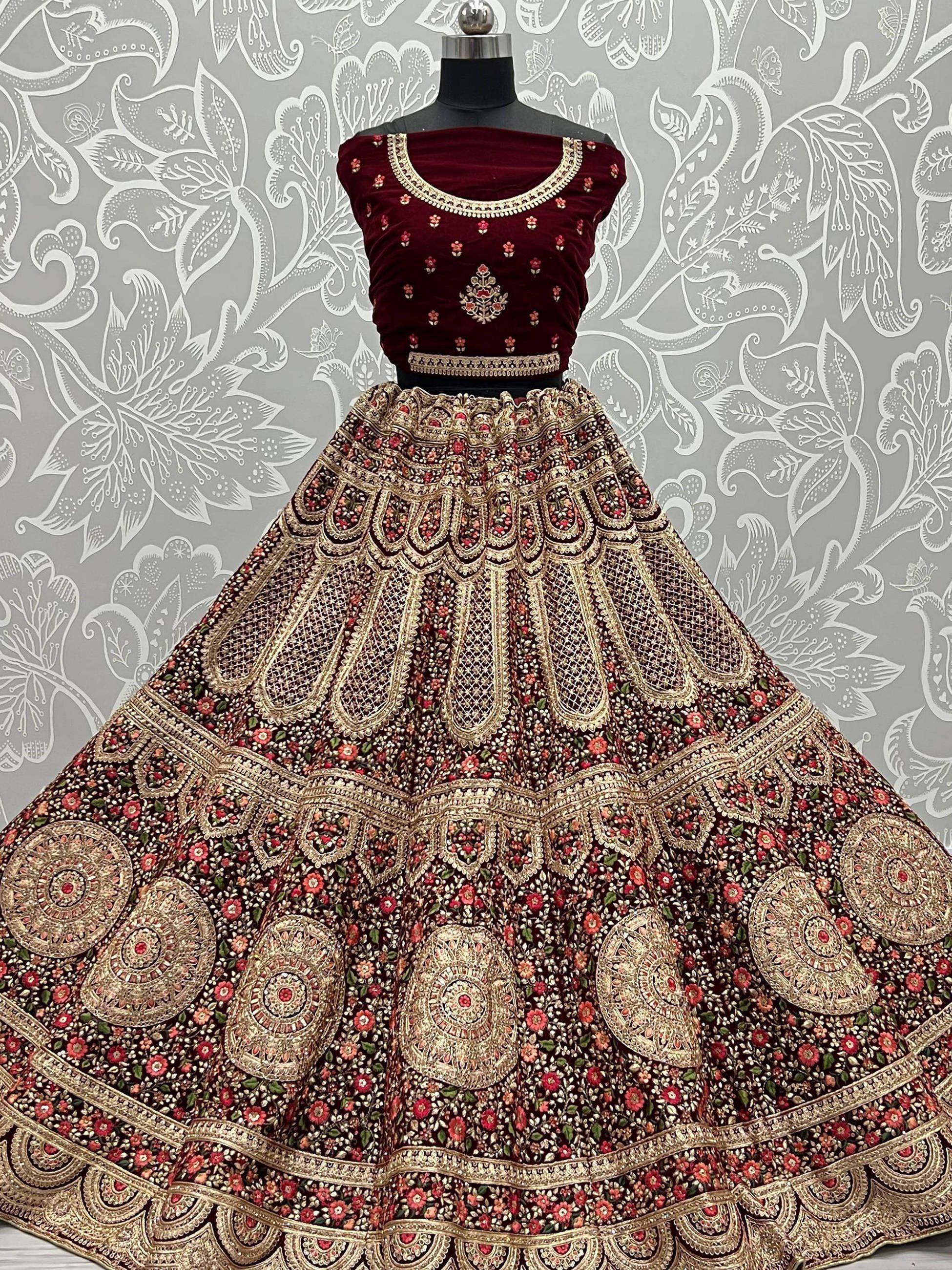 Maroon velvet designer lehenga choli with heavy gold embroidery and floral motifs, perfect for Indian weddings