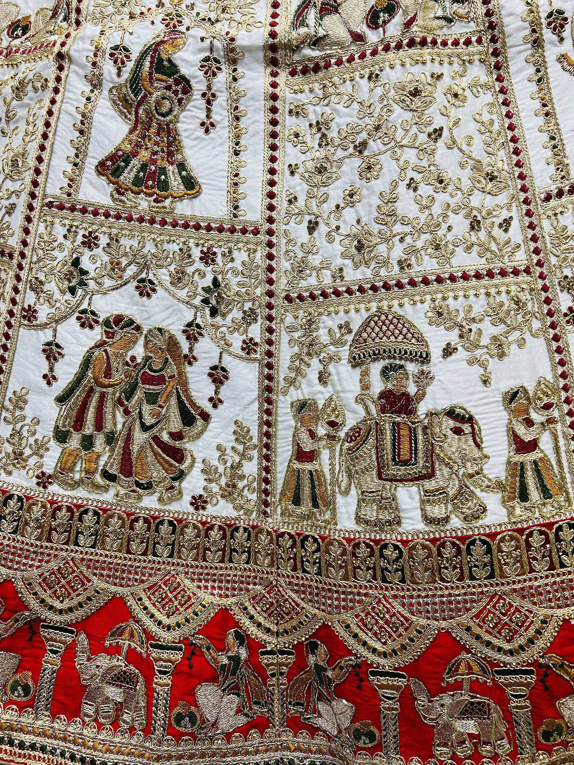 Intricate Indian ethnic embroidery with royal figures, elephants, and floral motifs on white and red fabric
