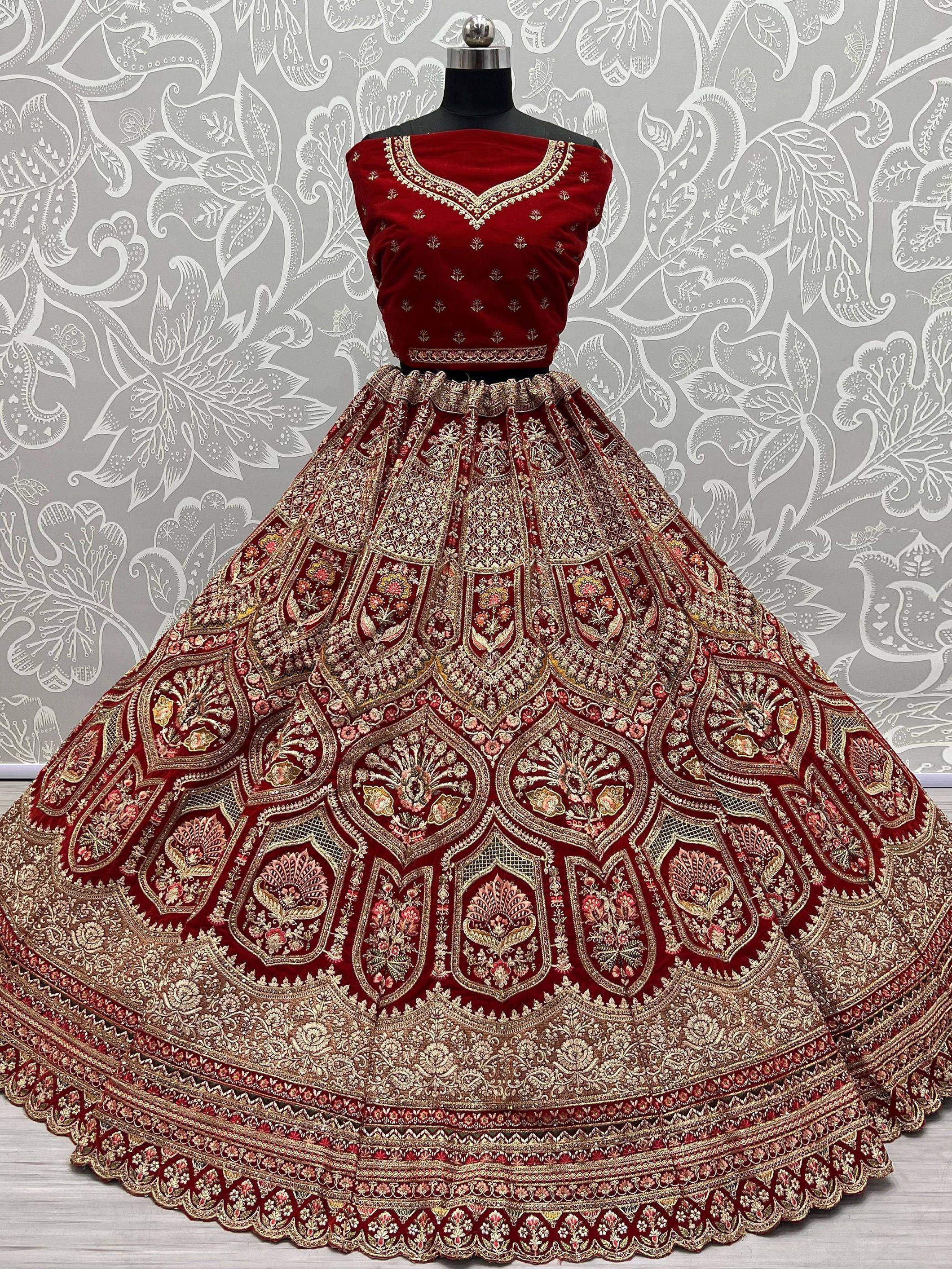 Red velvet designer lehenga choli with heavy gold embroidery, perfect for Indian weddings and festive occasions.