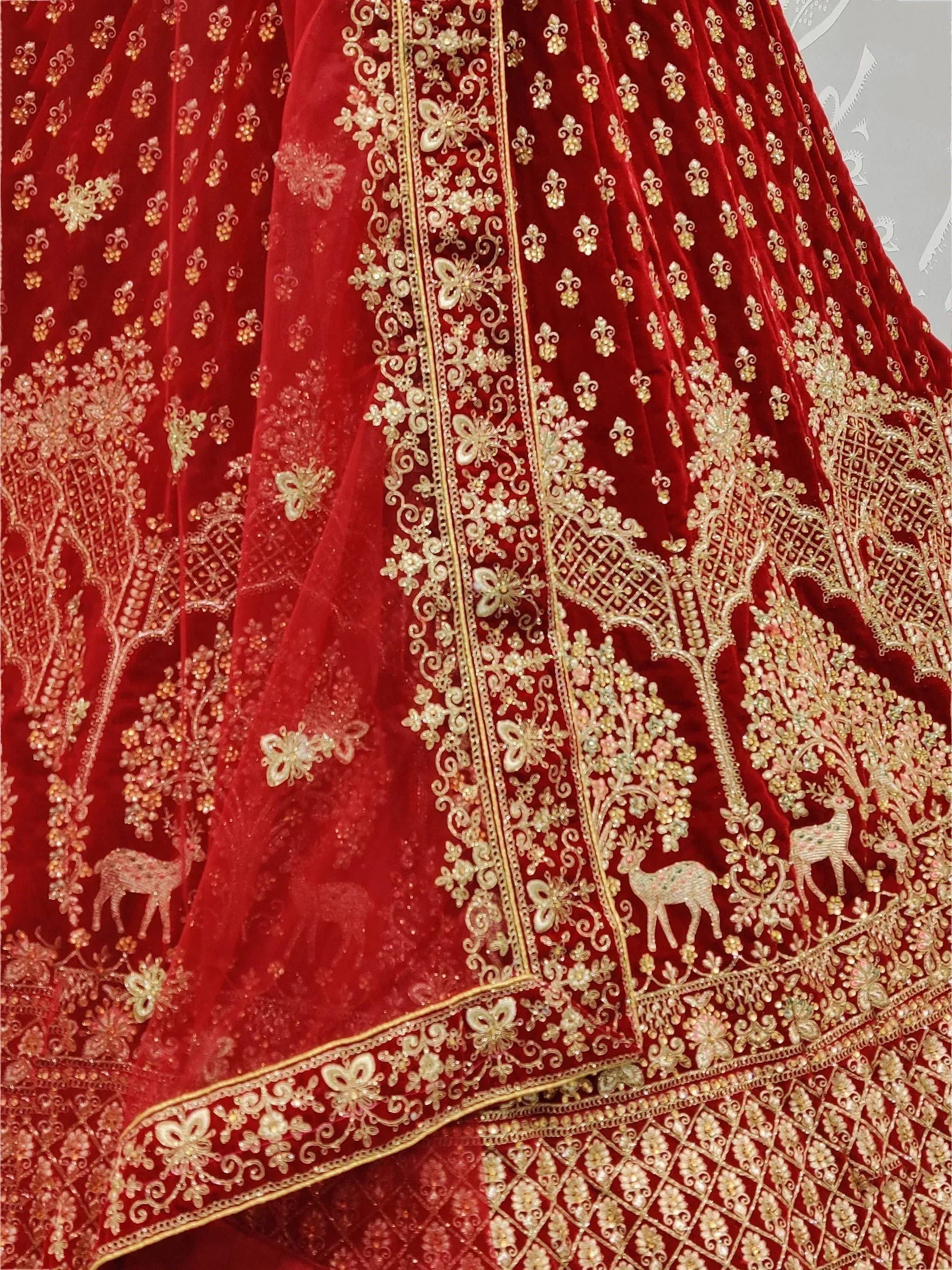 Red velvet lehenga with gold embroidery, deer motifs, and floral patterns for Indian ethnic wear