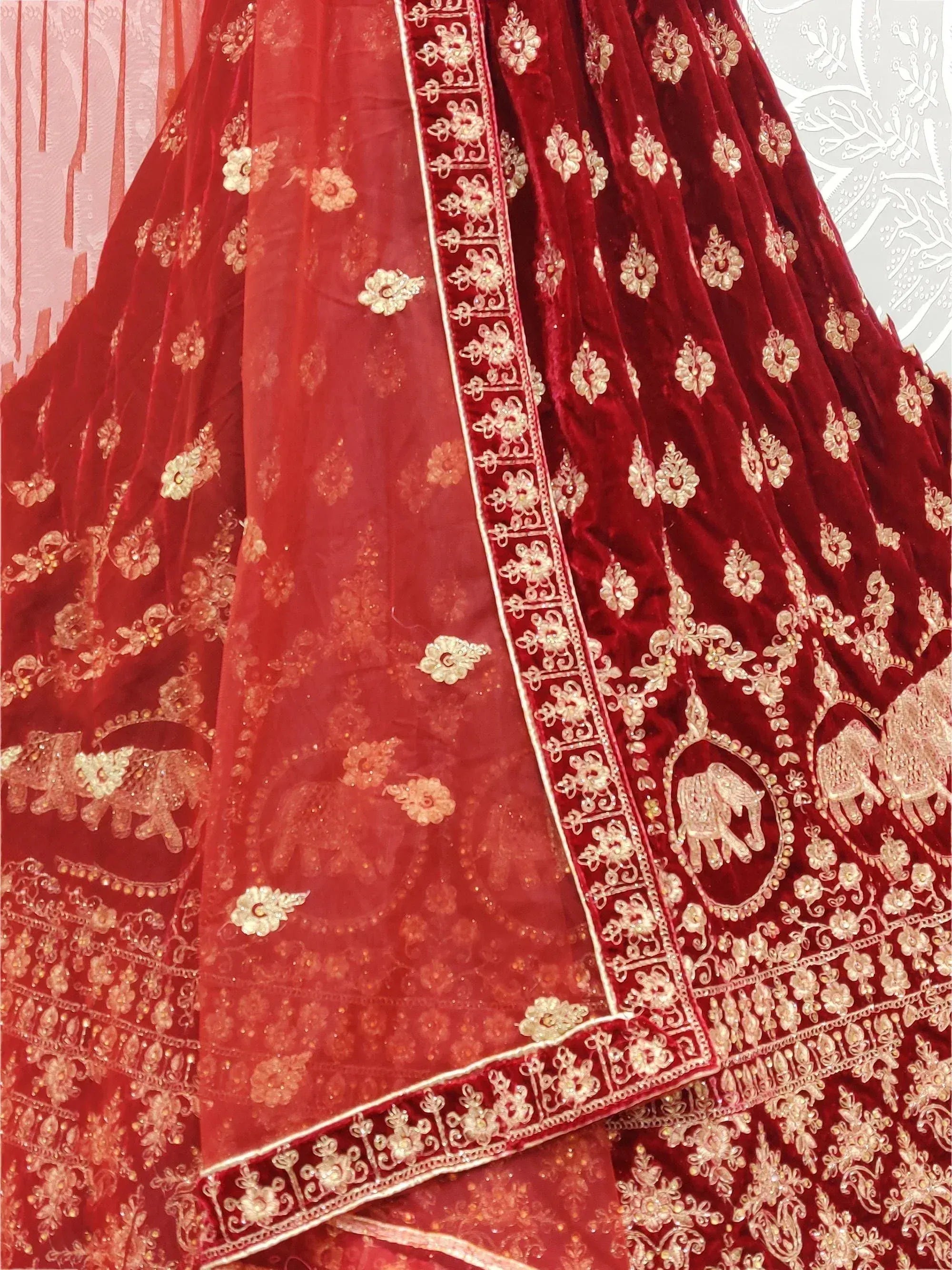 Red velvet lehenga with gold floral and elephant embroidery, perfect for Indian weddings and ethnic events.