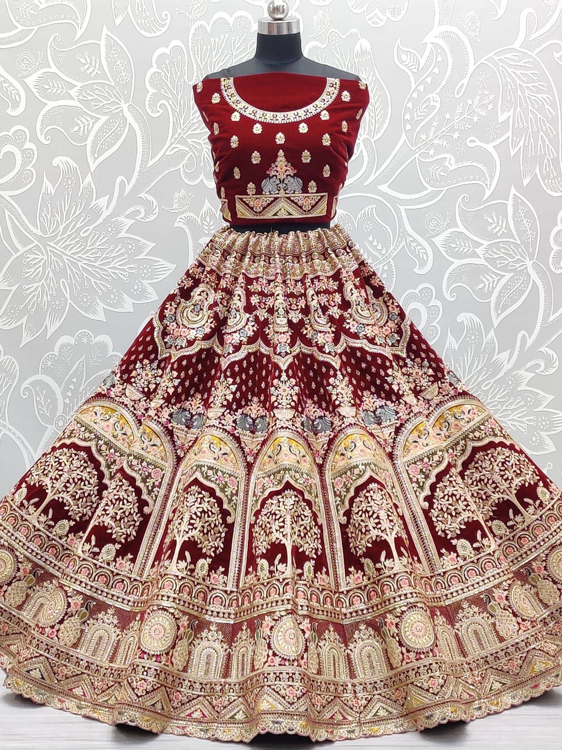 Maroon velvet lehenga choli with intricate gold embroidery and floral motifs, perfect for Indian weddings and festive occasions.