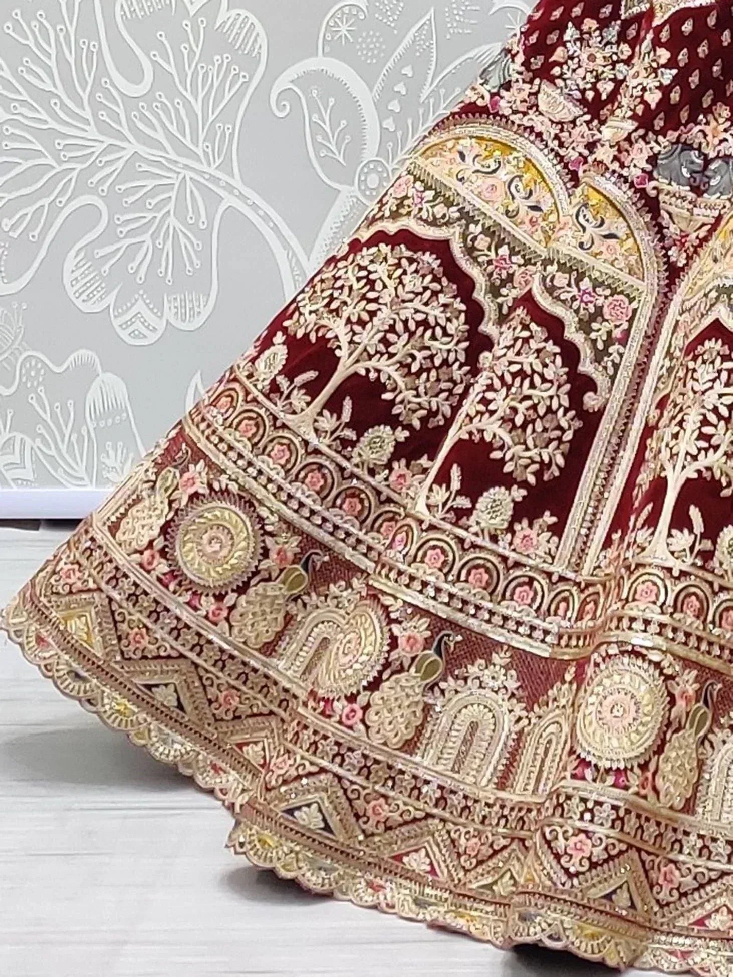 Maroon velvet lehenga with intricate gold embroidery, floral motifs, and peacock designs for Indian ethnic wear.
