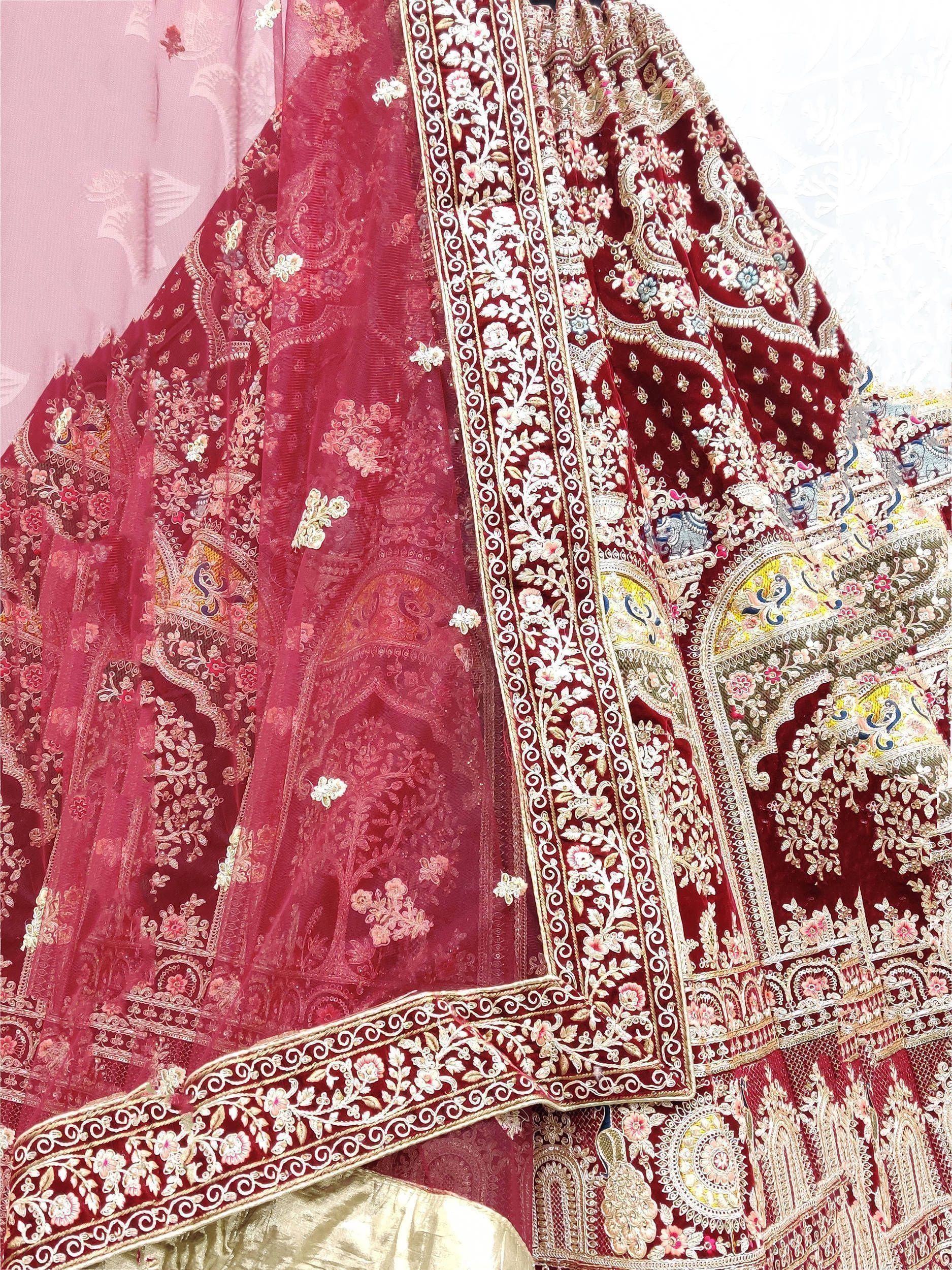 Luxury maroon velvet lehenga with intricate floral embroidery and sheer dupatta, perfect for Indian weddings.