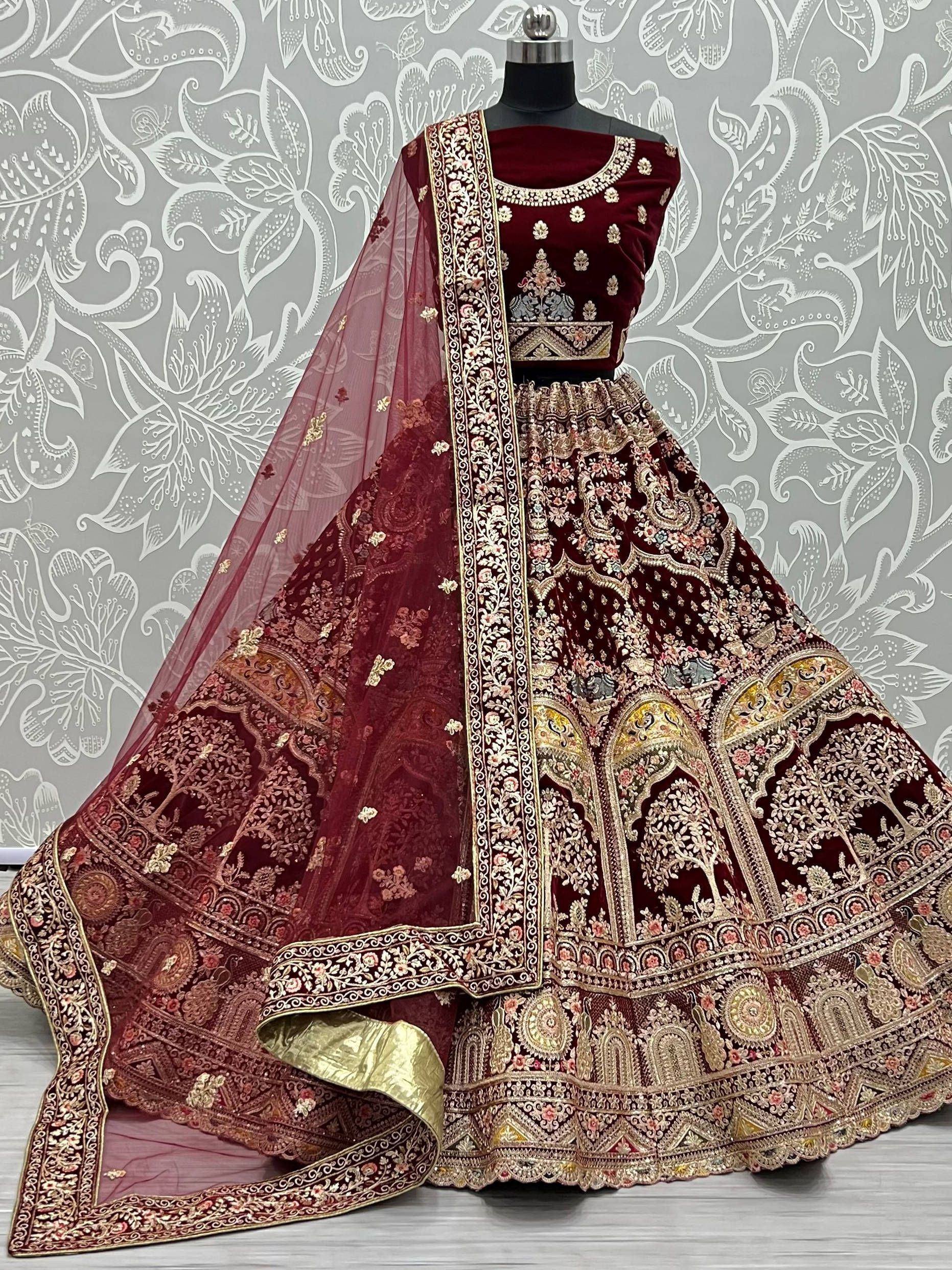 Maroon velvet designer lehenga choli with heavy gold embroidery and matching dupatta, ideal for weddings and festive occasions.