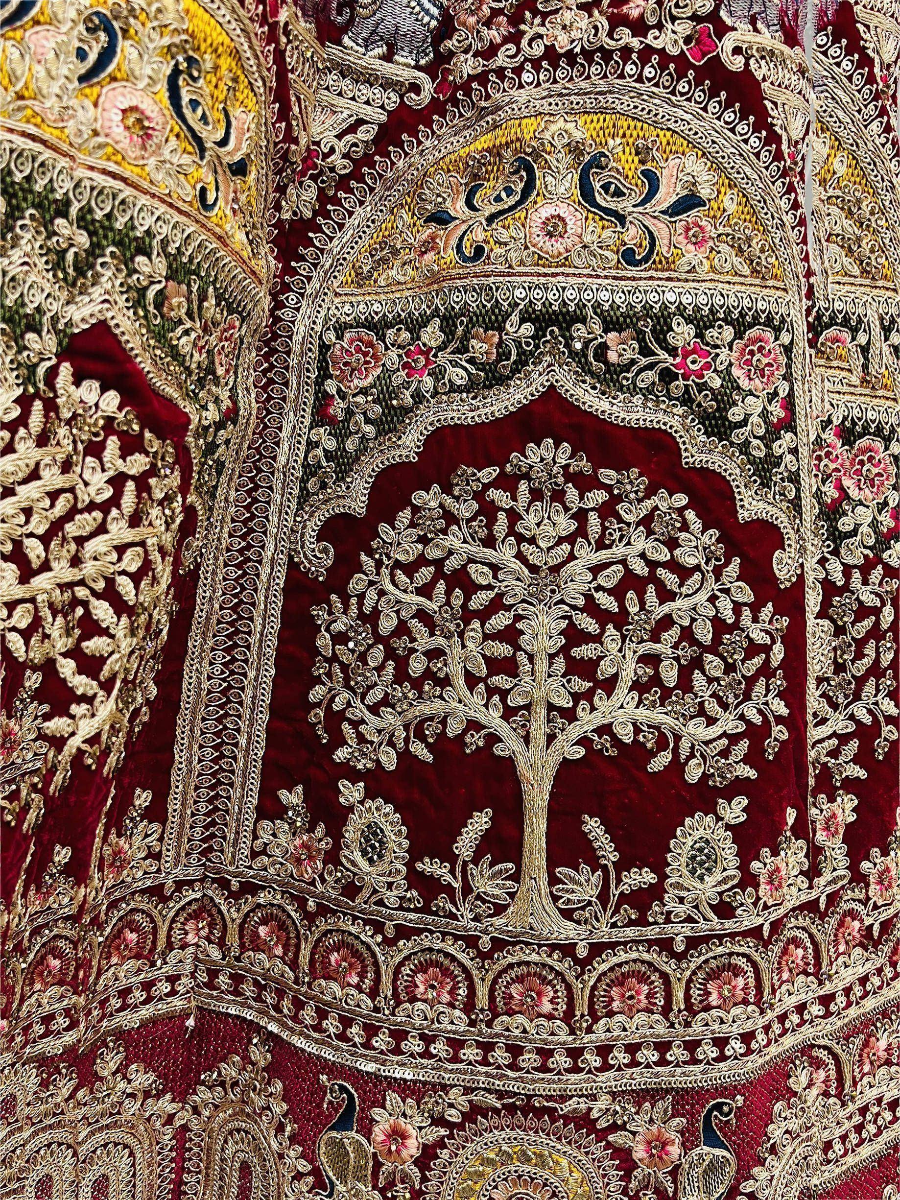 Richly embroidered Indian ethnic wear with tree and peacock motifs on maroon velvet, perfect for festive occasions.