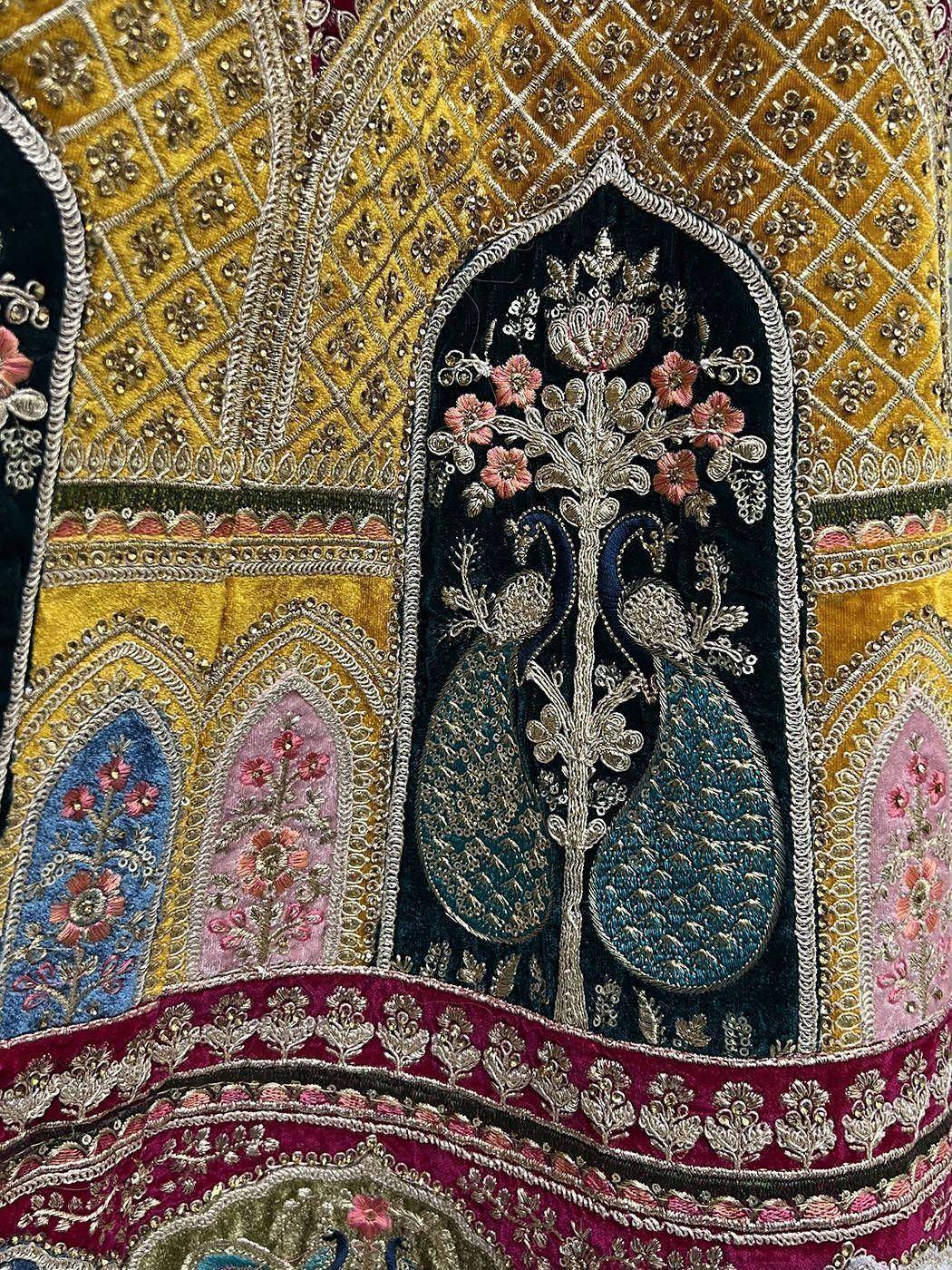 Luxury Indian ethnic wear with intricate gold embroidery, floral motifs, and peacock design on velvet fabric.
