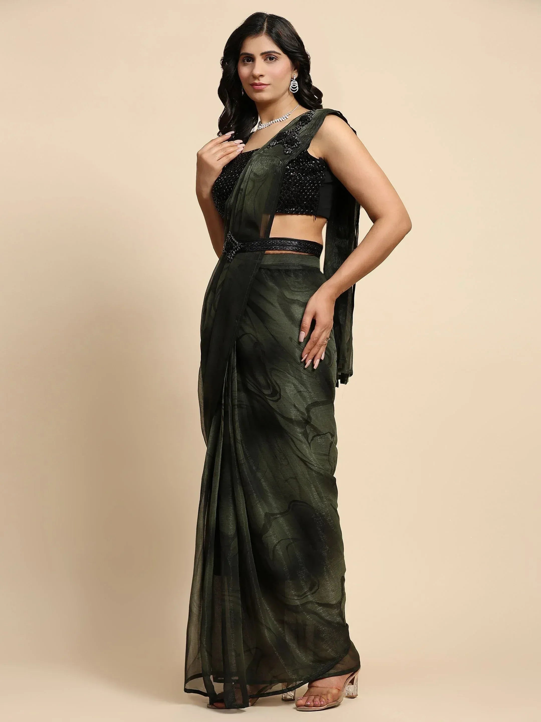 Woman in dark green sheer saree with black sequined blouse, elegant ethnic wear for festive occasions