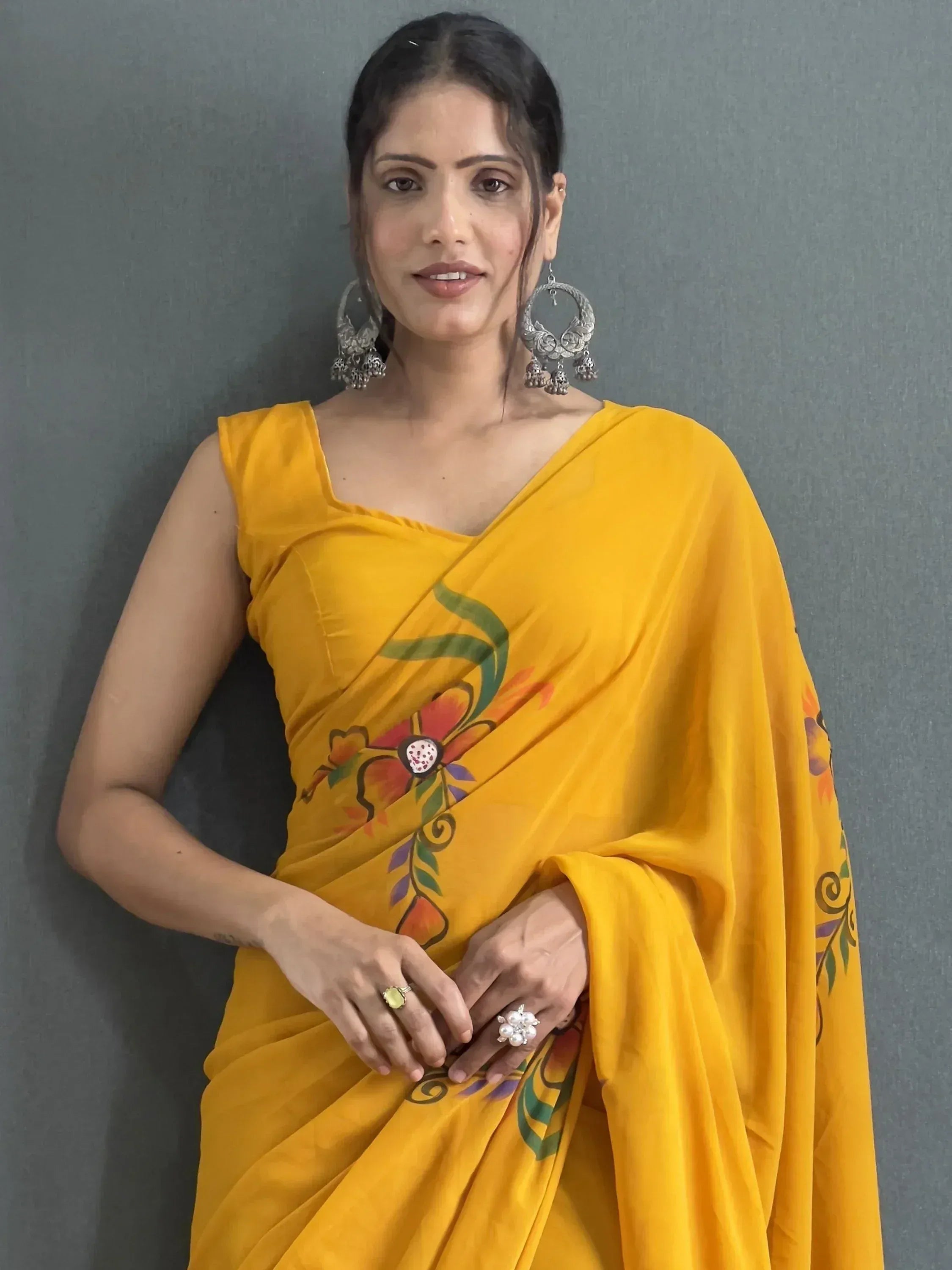 Woman in vibrant yellow floral saree with silver jhumka earrings, Indian ethnic wear