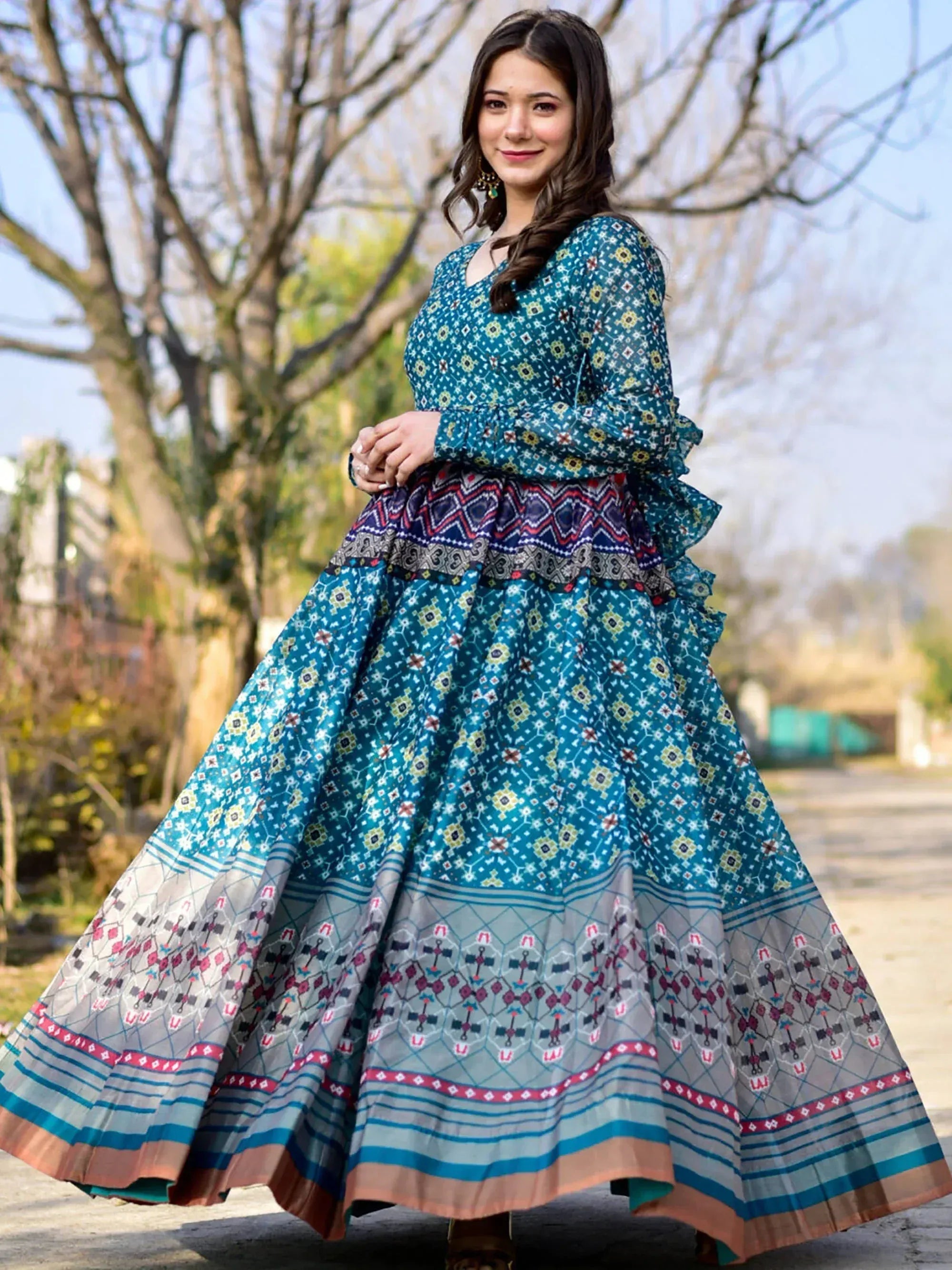 Teal printed ethnic gown with ruffled sleeves and geometric border, perfect for Indian festive occasions