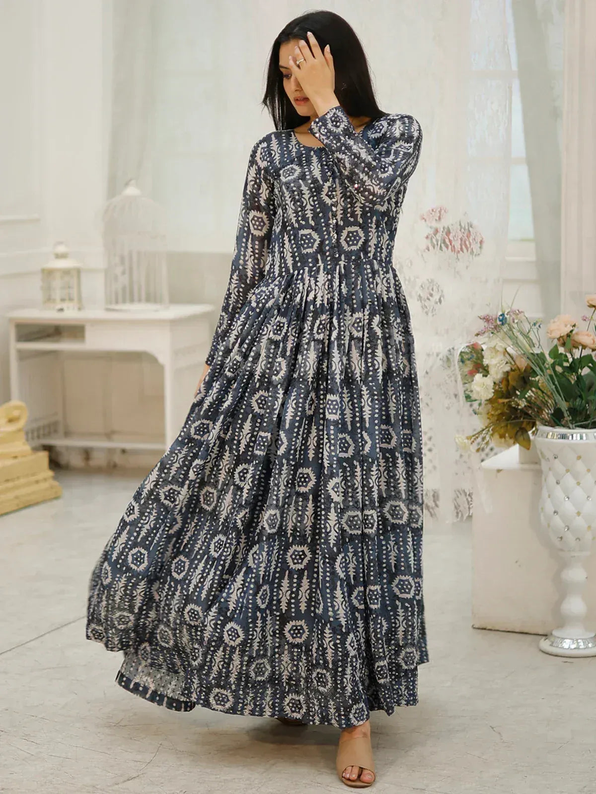 Woman in navy blue printed ethnic gown with long sleeves and flared skirt, perfect for Indian occasions.
