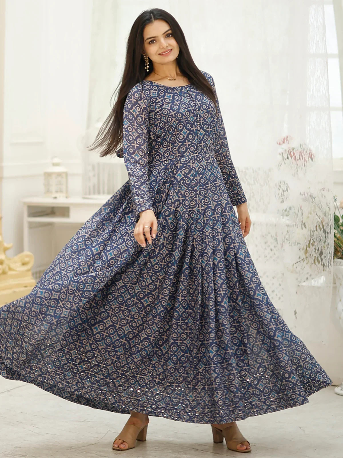 Woman in long blue printed ethnic gown with full sleeves twirling indoors