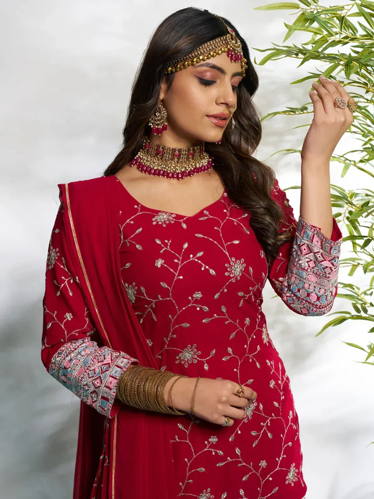 Red embroidered salwar kameez with floral detailing, traditional jewelry, and matching dupatta for Indian ethnic wear