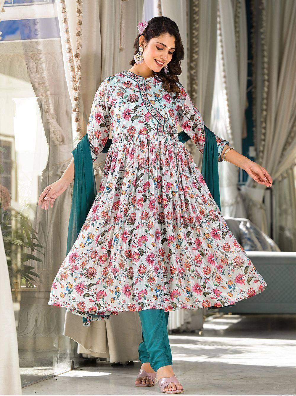 Woman wearing floral print Anarkali suit with teal churidar and dupatta, posing indoors