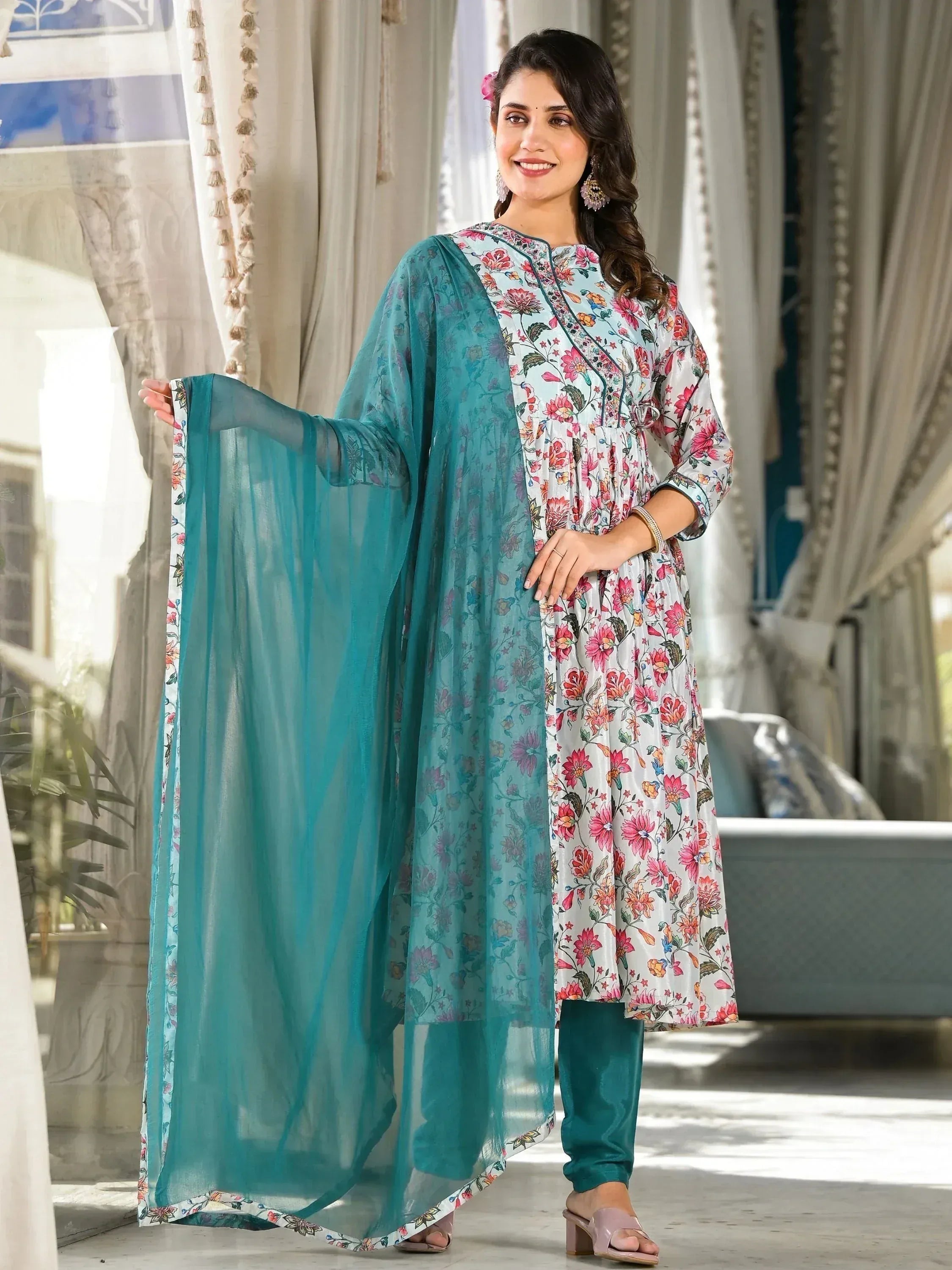 Woman wearing floral printed salwar kameez with teal dupatta in a modern Indian living room