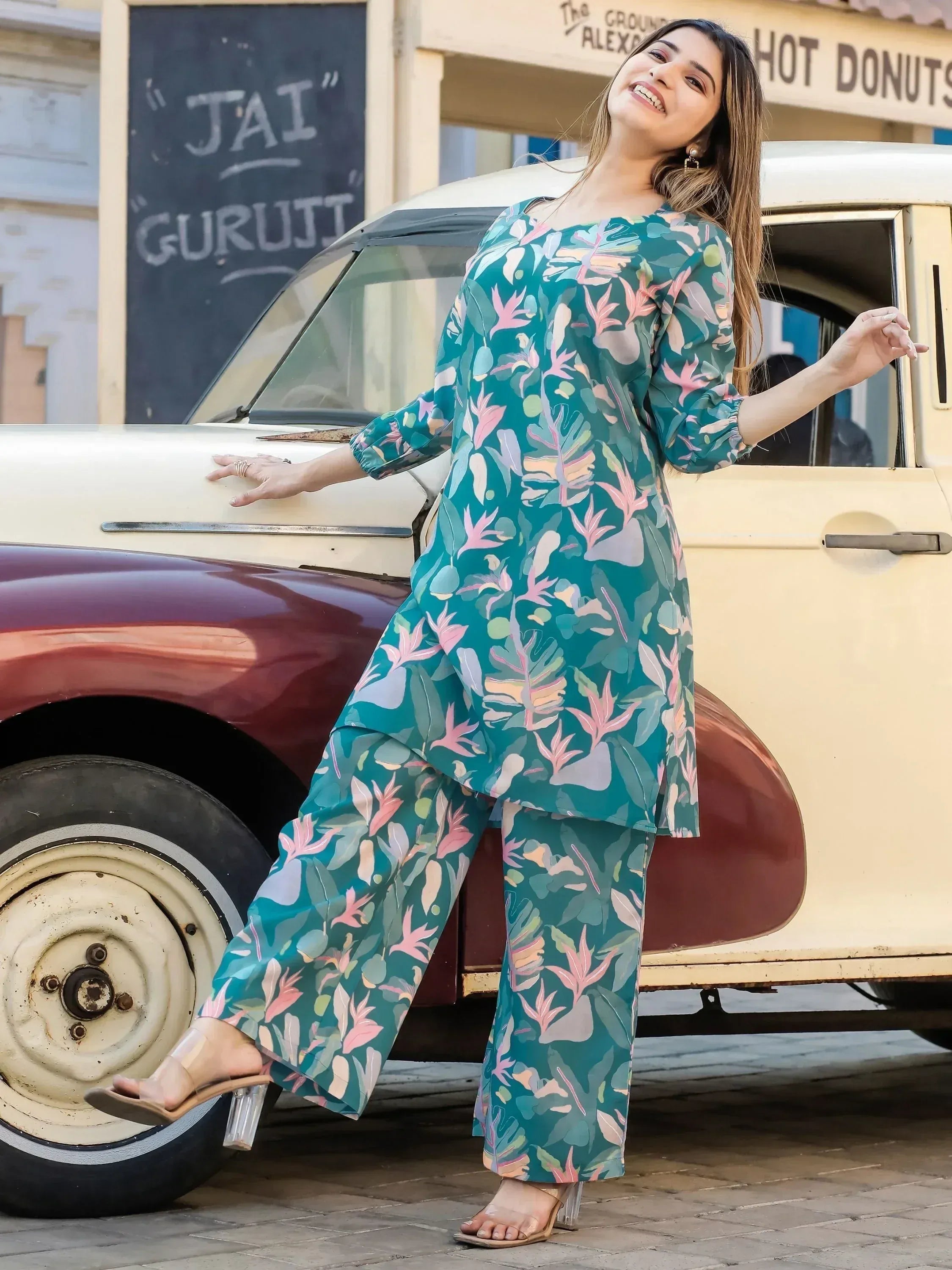 Woman in teal floral print salwar kameez posing by vintage car, stylish ethnic wear