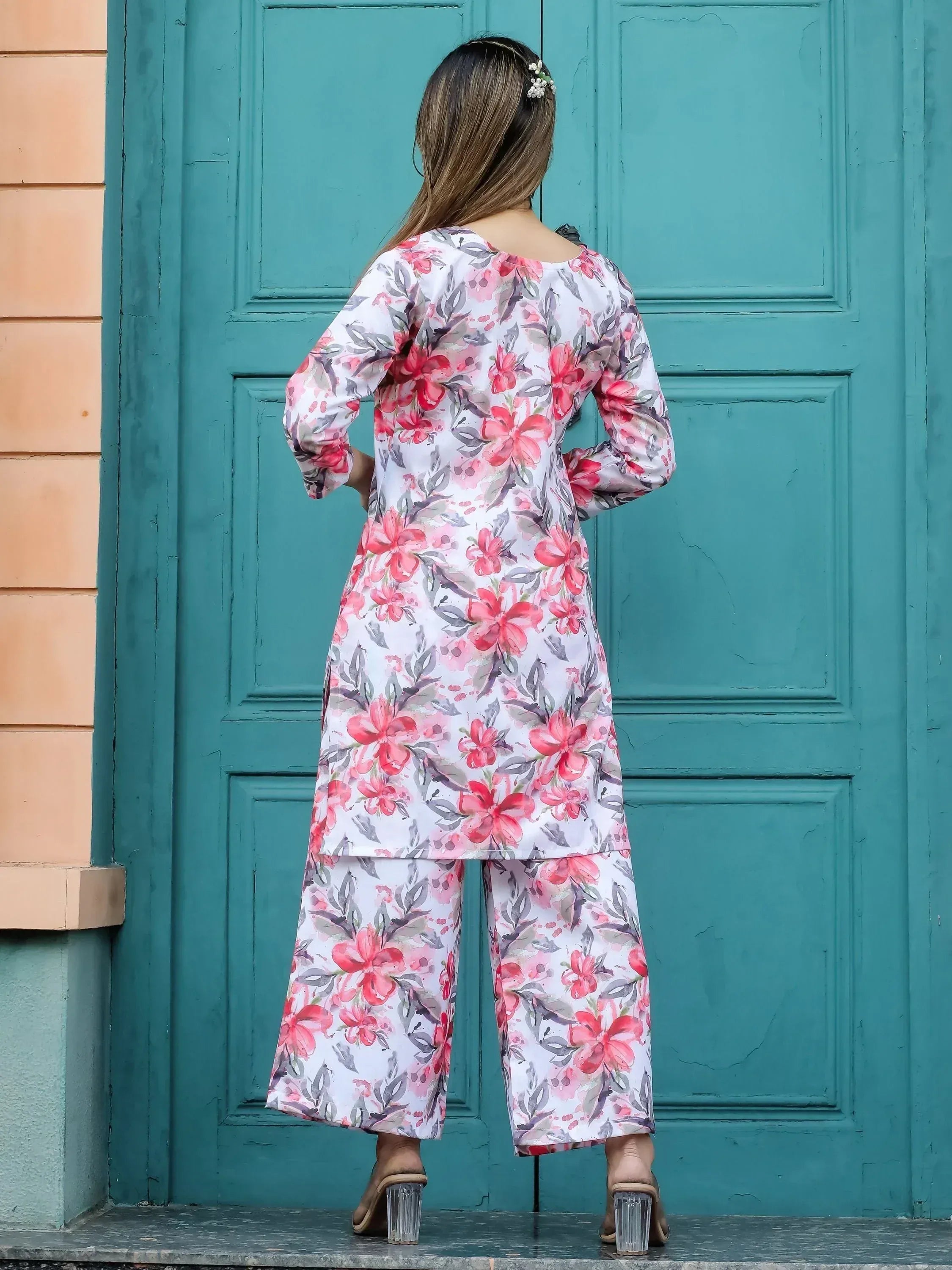 Floral print salwar kameez with pink flowers, back view against teal door