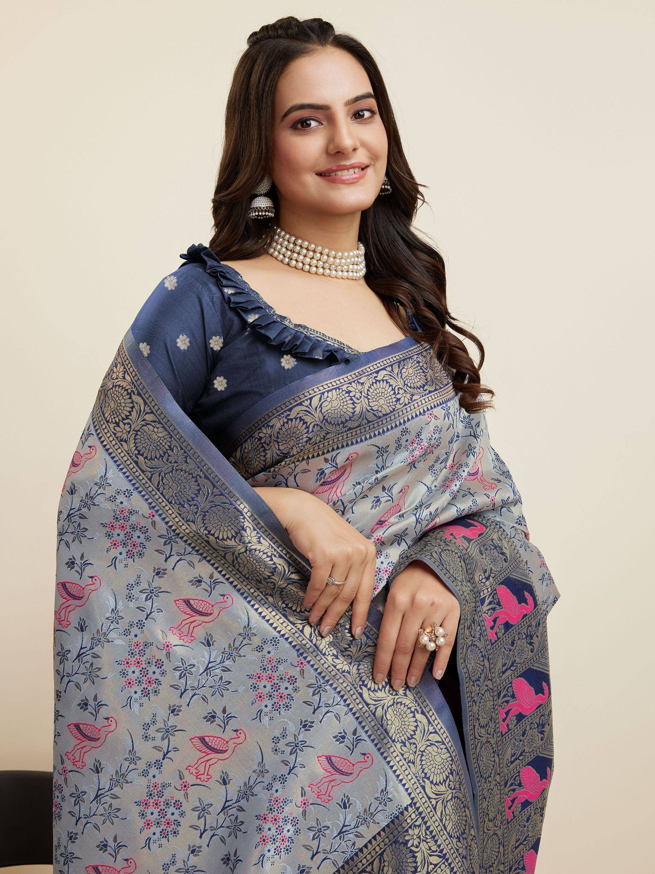 Woman in elegant blue saree with pink bird and floral print, gold border, ruffled blouse, pearl jewelry