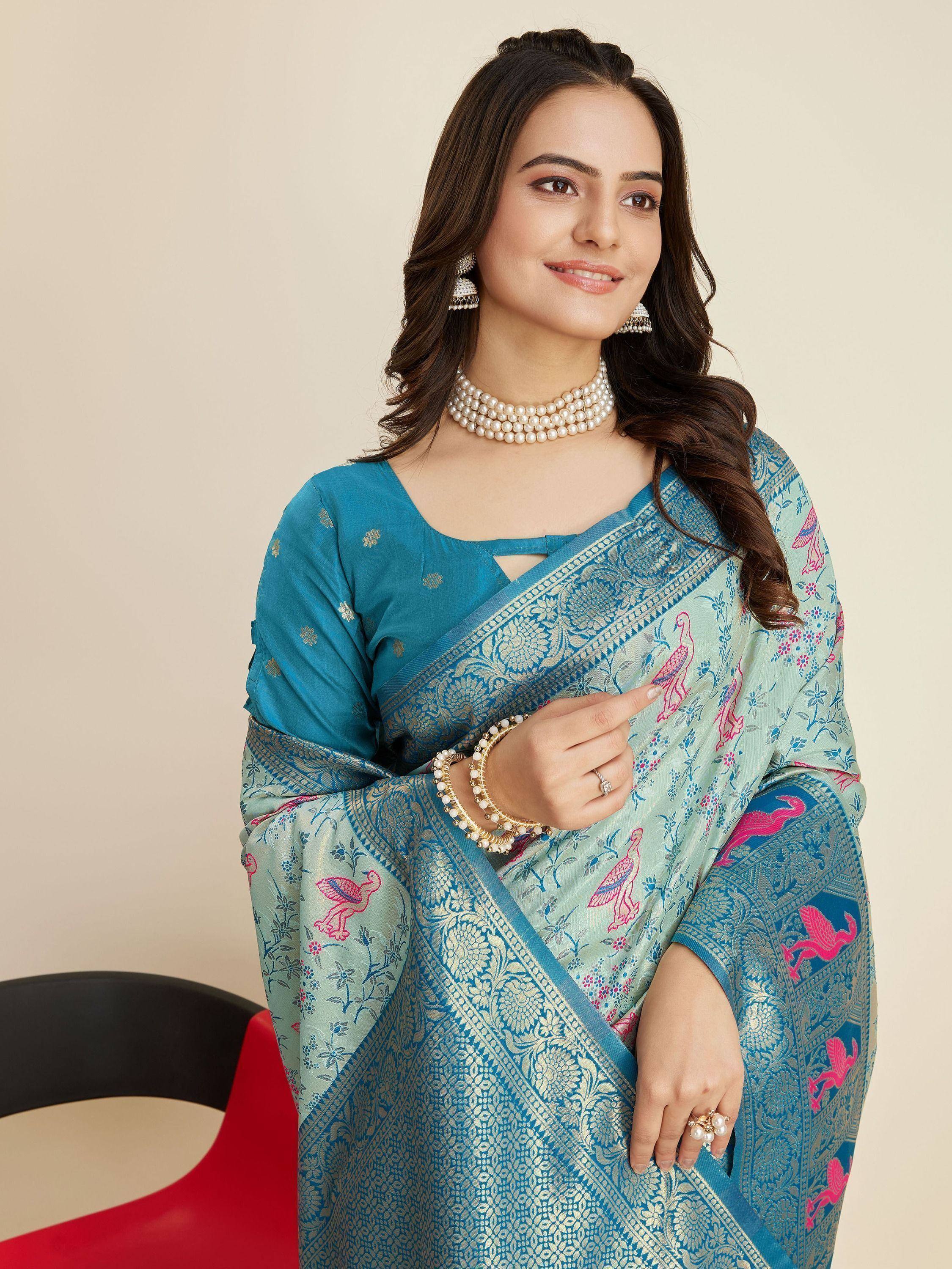 Woman in blue and mint saree with pink bird print, gold border, and pearl jewelry, Indian ethnic wear