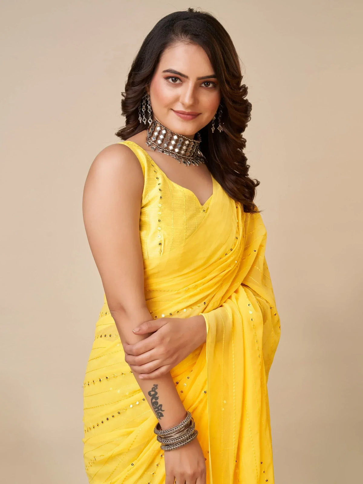 Yellow ethnic saree with sequin detailing, paired with mirror work choker and statement earrings