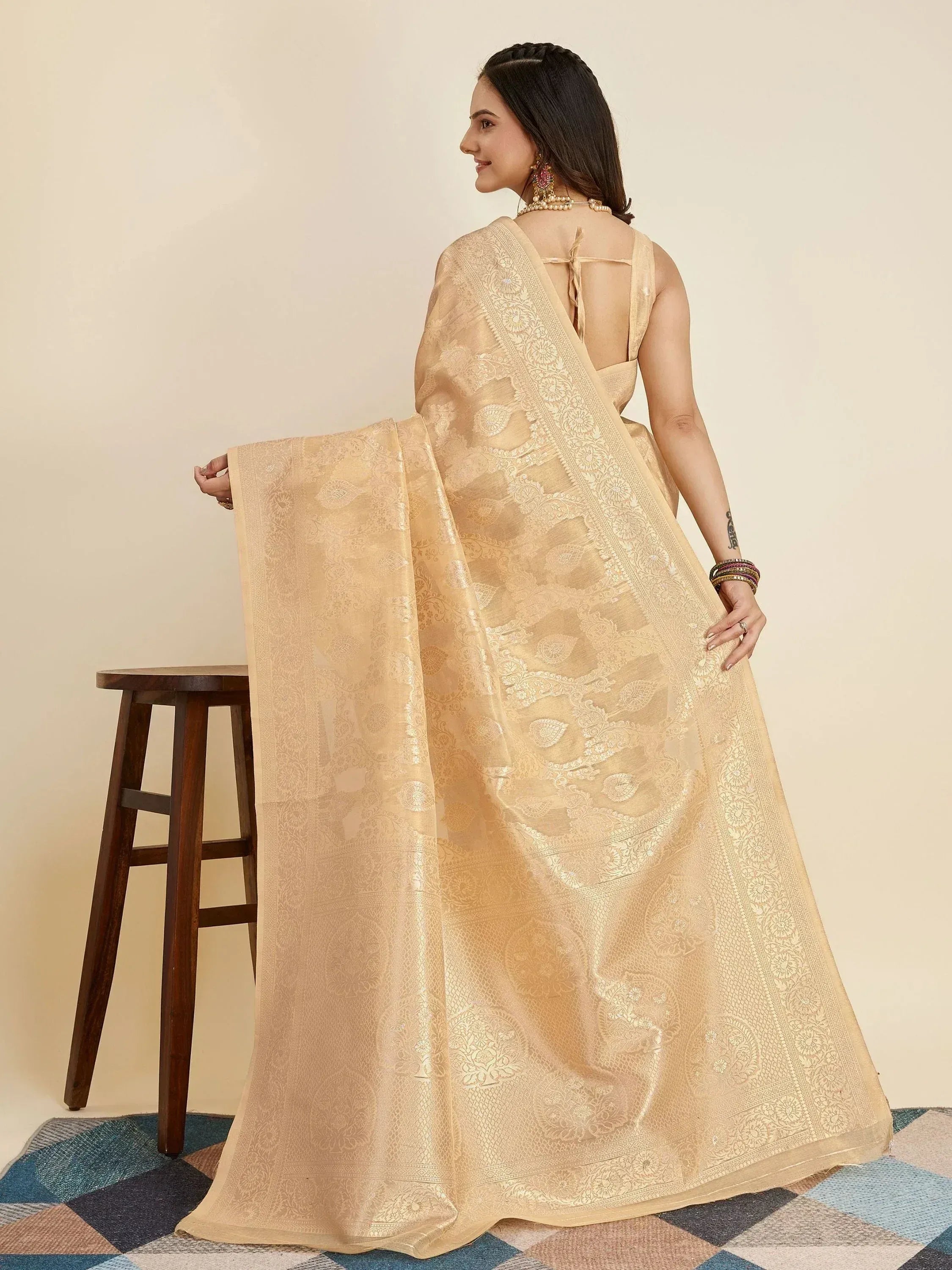 Elegant beige designer saree with intricate gold embroidery, perfect for Indian ethnic wear occasions.