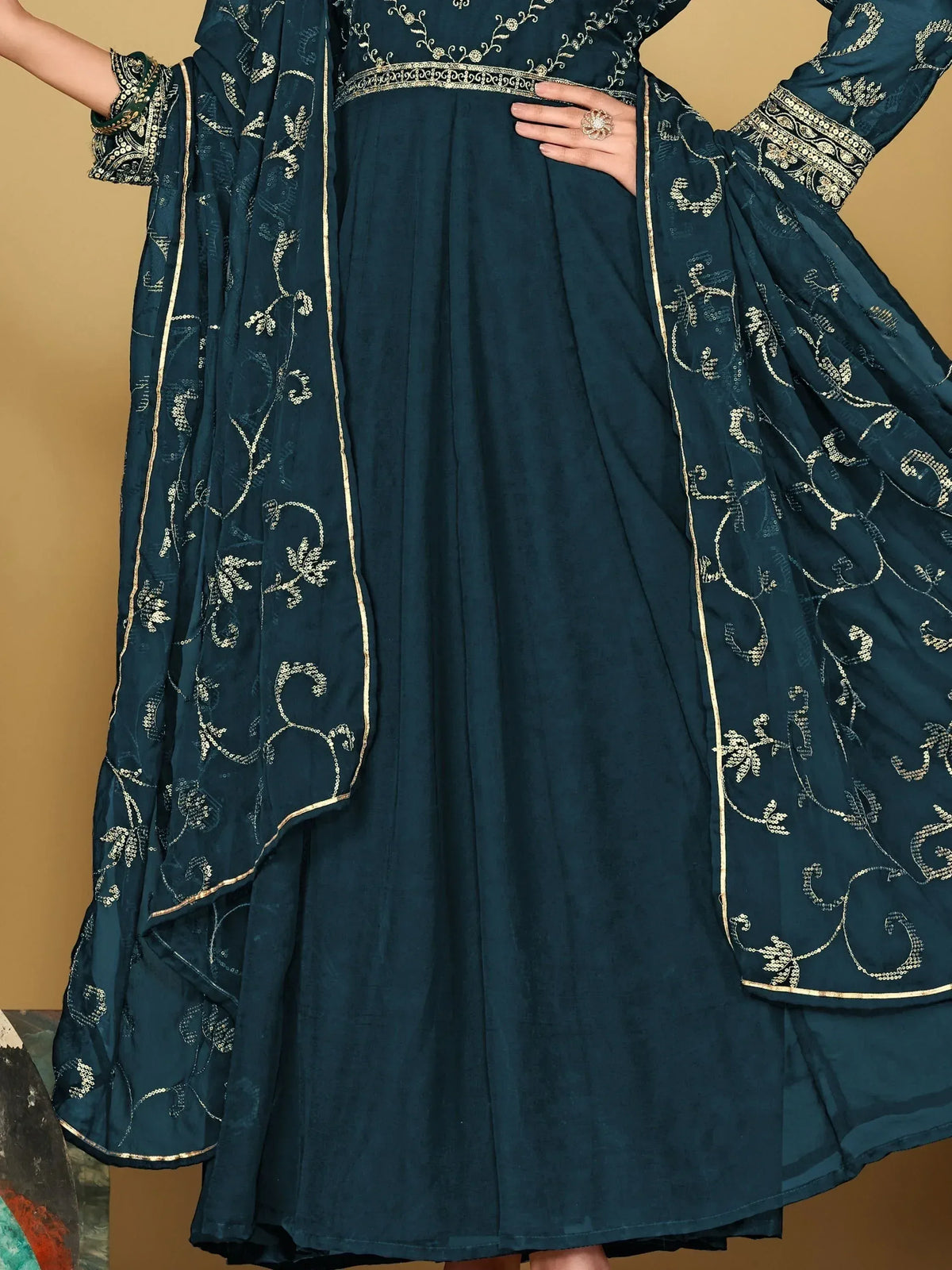 Dark teal ethnic anarkali with gold embroidery and floral dupatta, perfect for Indian weddings or festive occasions.