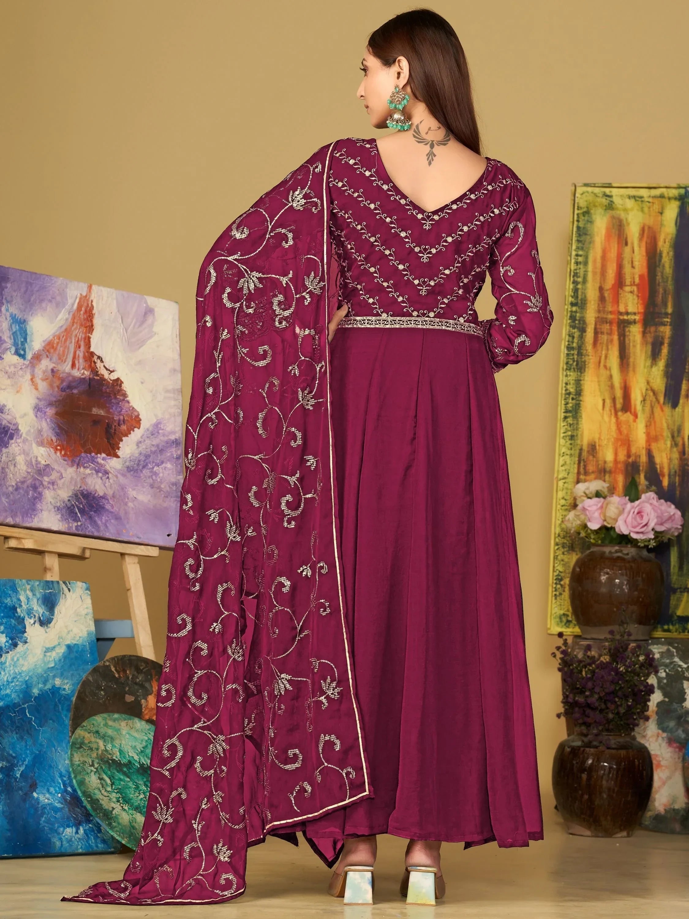 Woman in magenta embroidered ethnic gown with dupatta, silver heels, and green earrings
