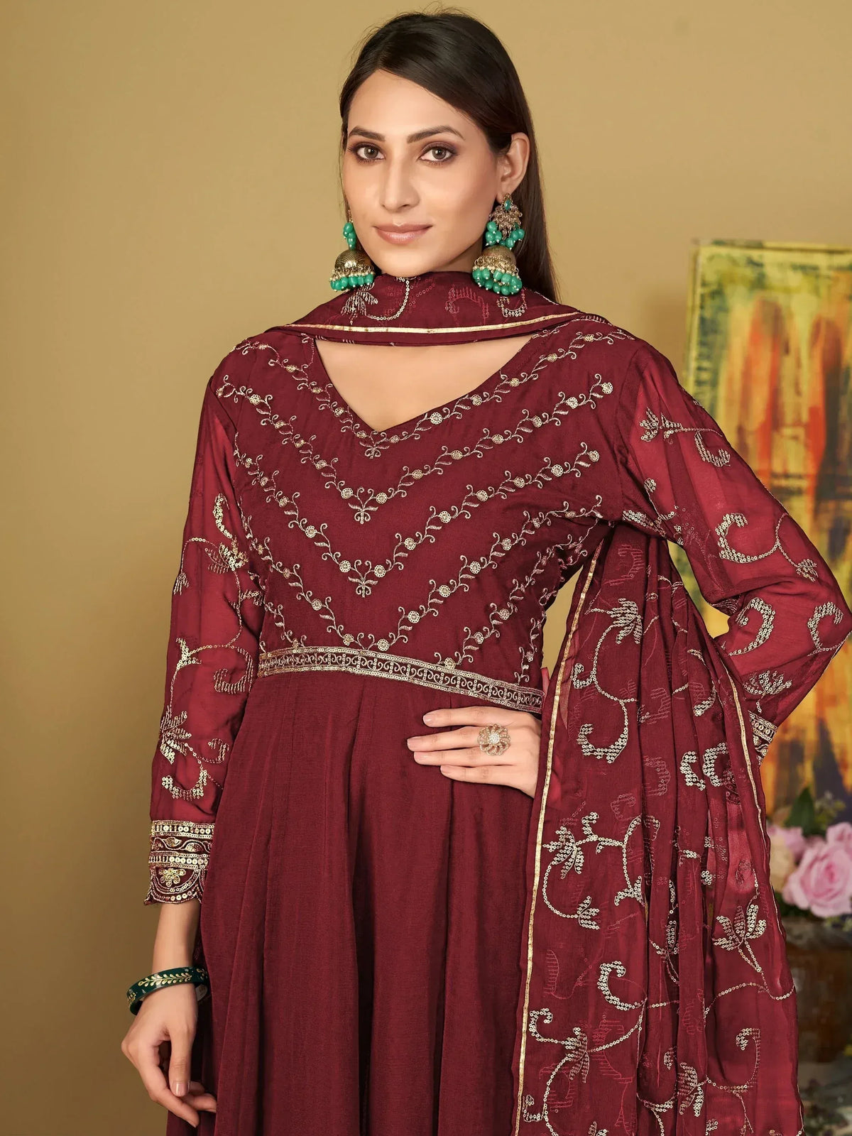 Woman wearing maroon embroidered ethnic gown with dupatta and statement earrings