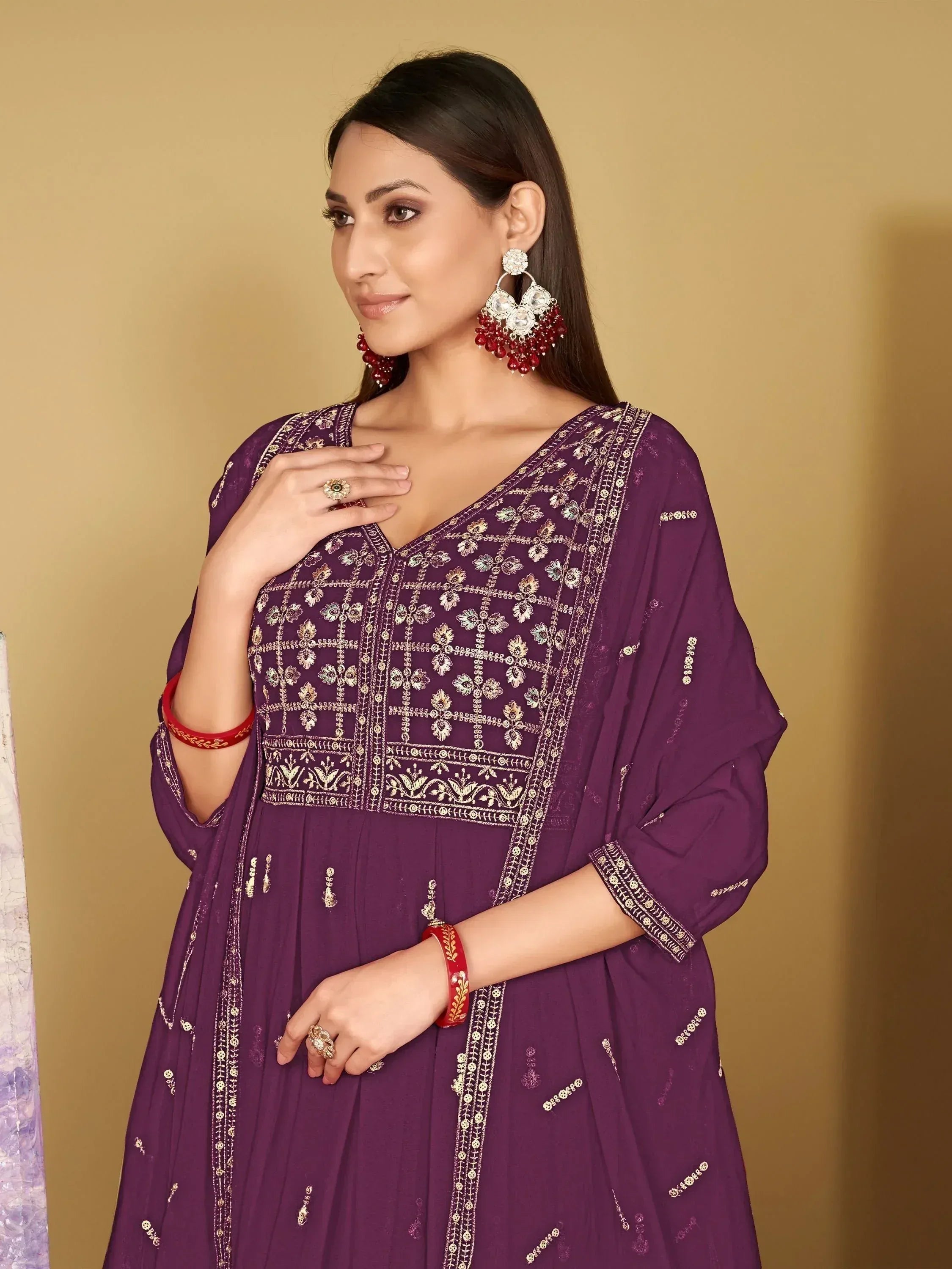 Purple embroidered ethnic gown with gold detailing and red jewelry